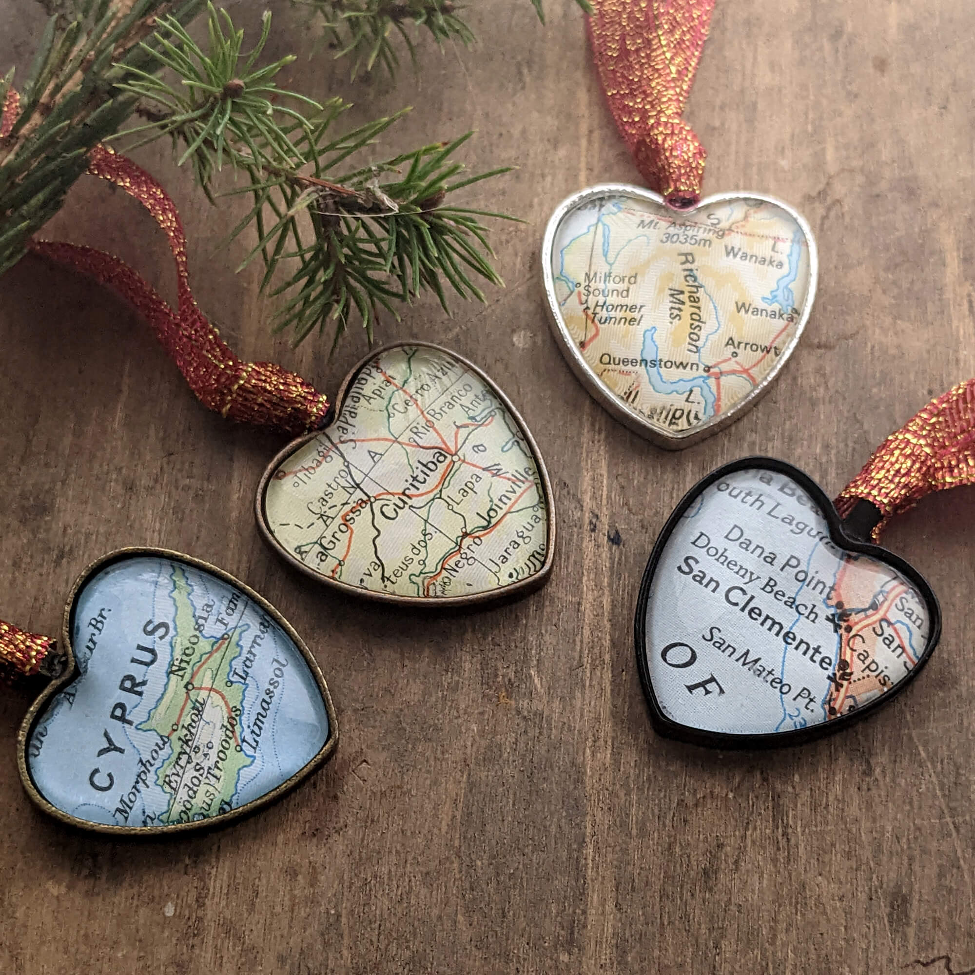 Four Christmas tree ornaments in heart shape featuring maps of the world