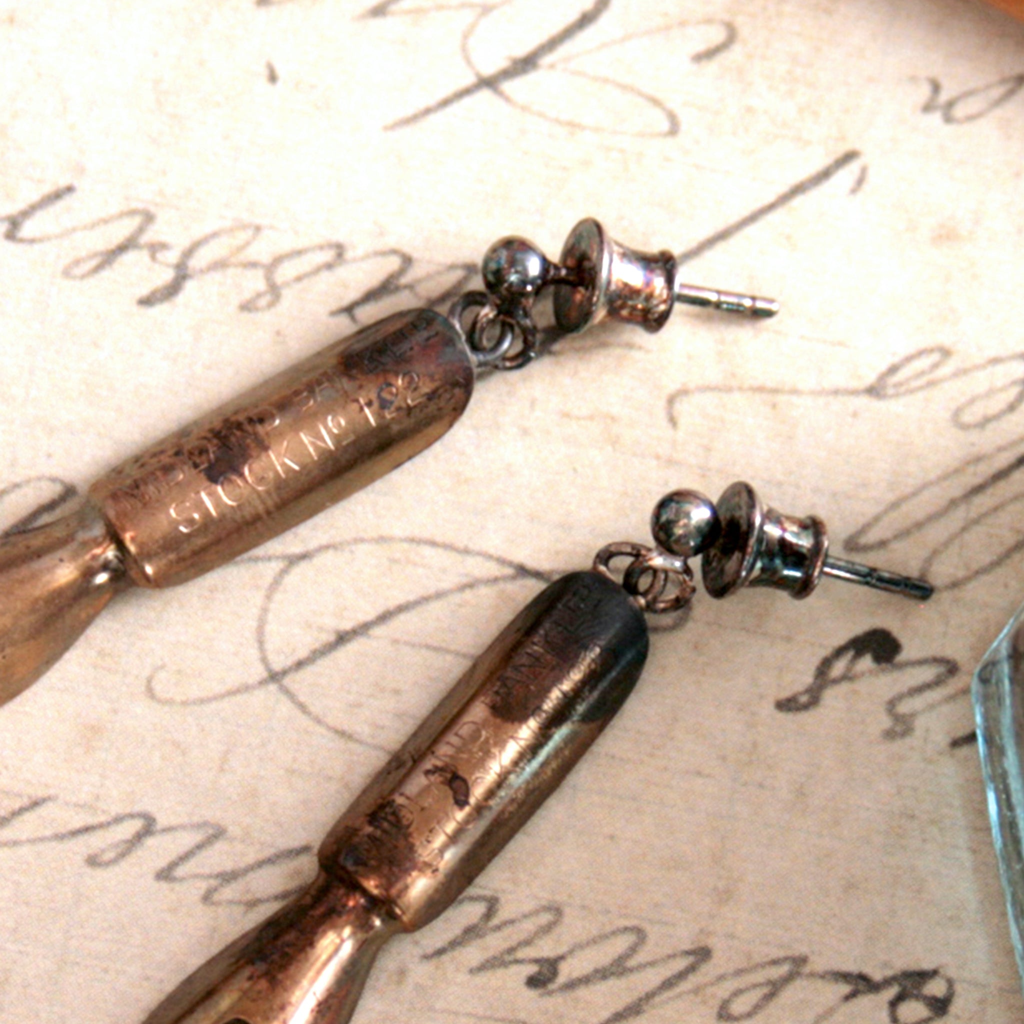 push back earring setting on real pen nibs lying on an old letter