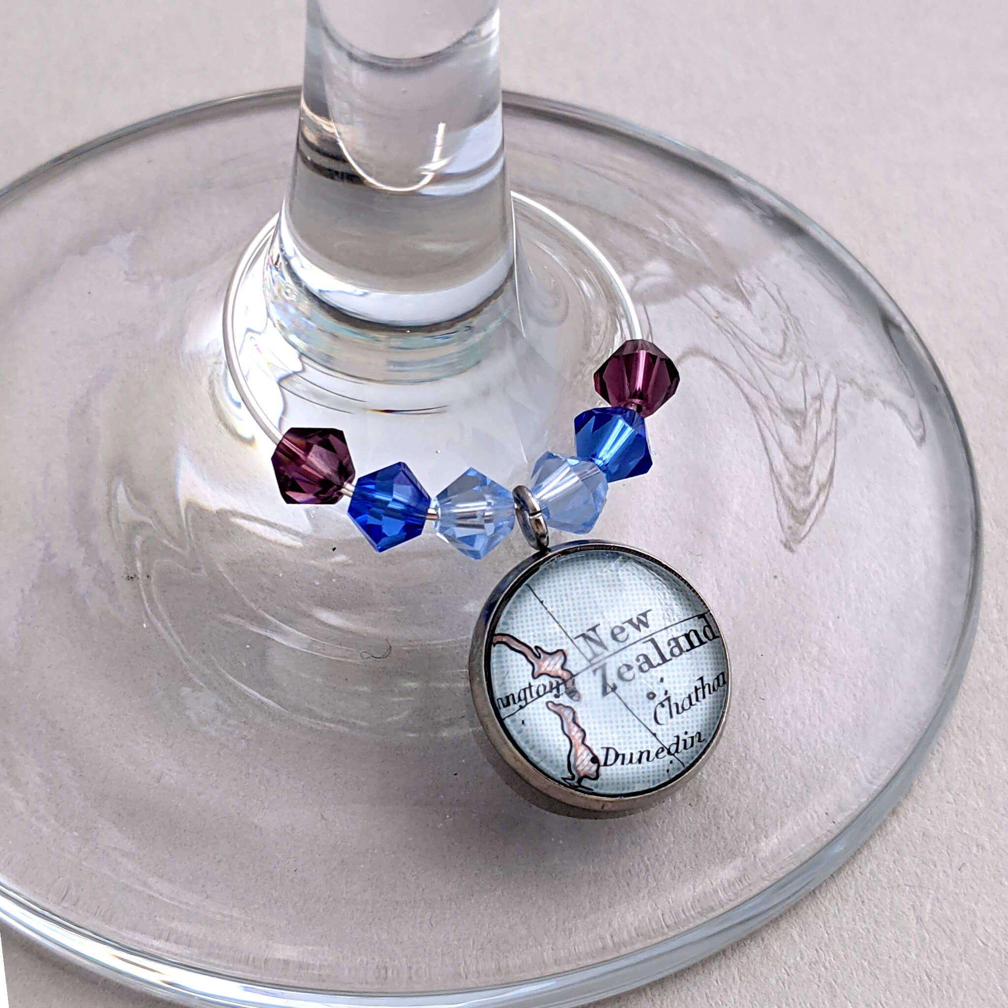 wine glass charm in violet and blue tone personalised with map of New Zealand