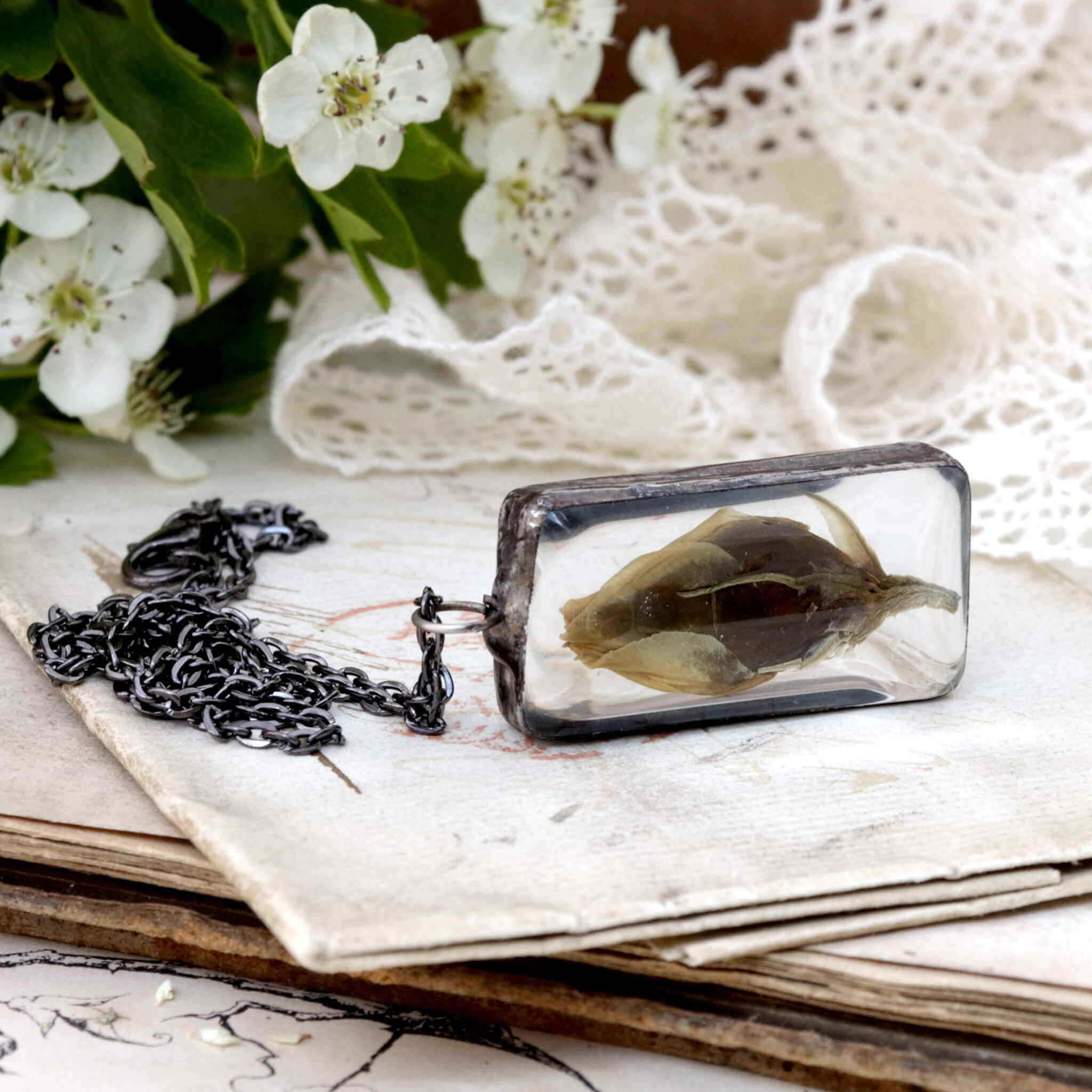 Eustoma flower bud framed in stained glass necklace lying on its side on an old letter