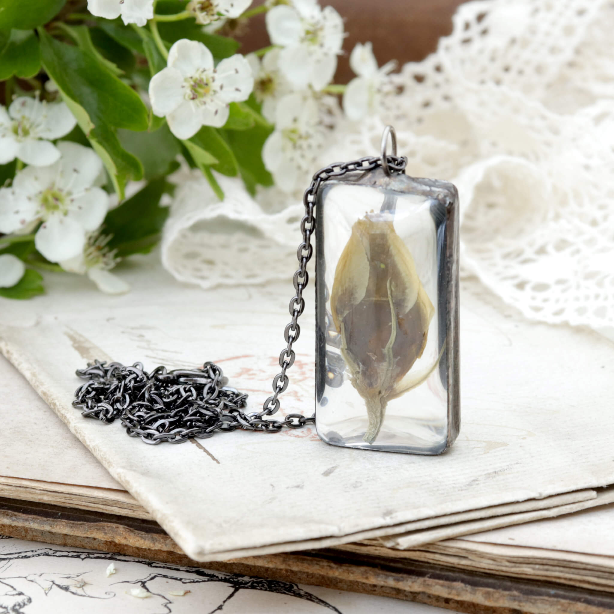 Eustoma flower bud framed in stained glass necklace on an old letter