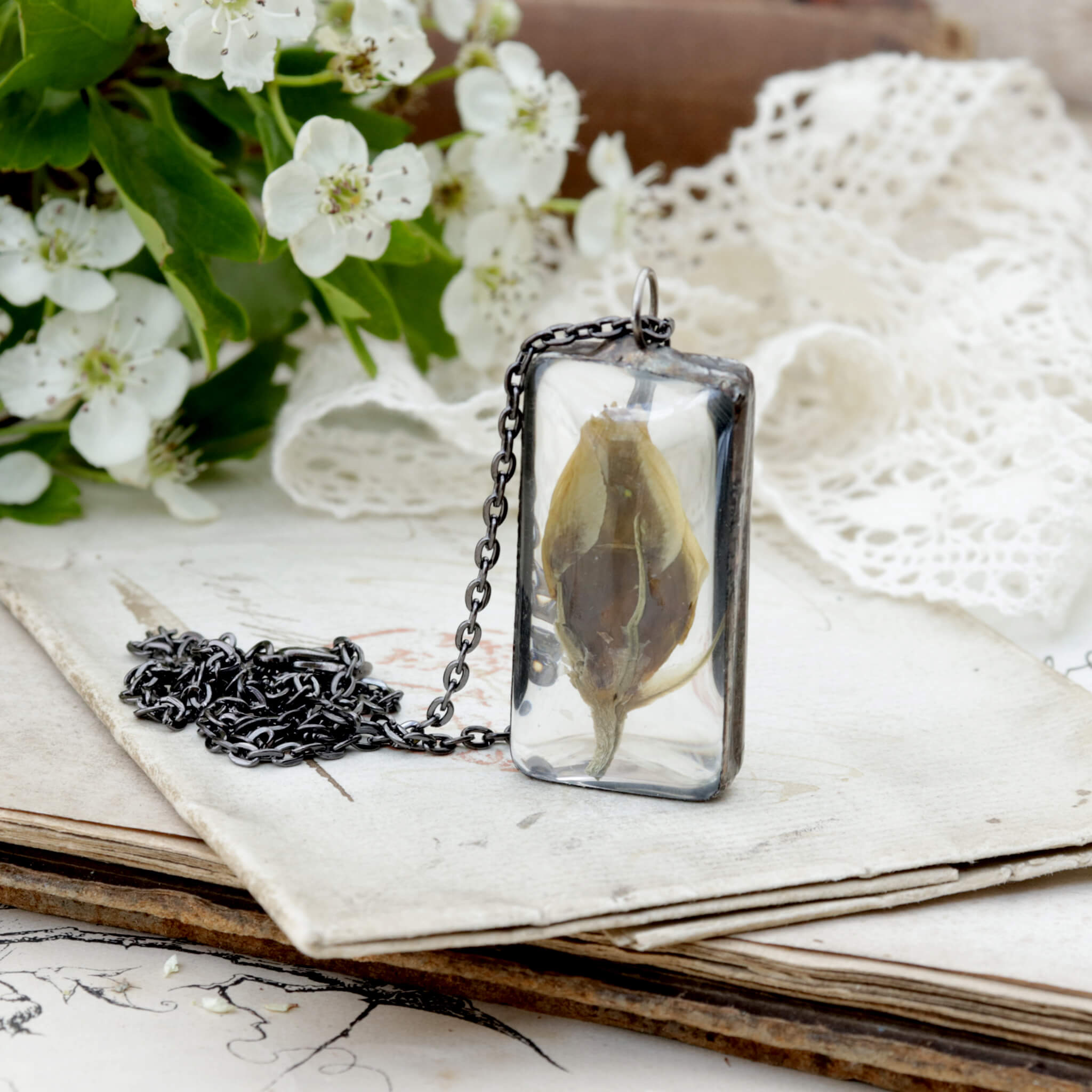 Eustoma flower bud framed in stained glass necklace on an old letter