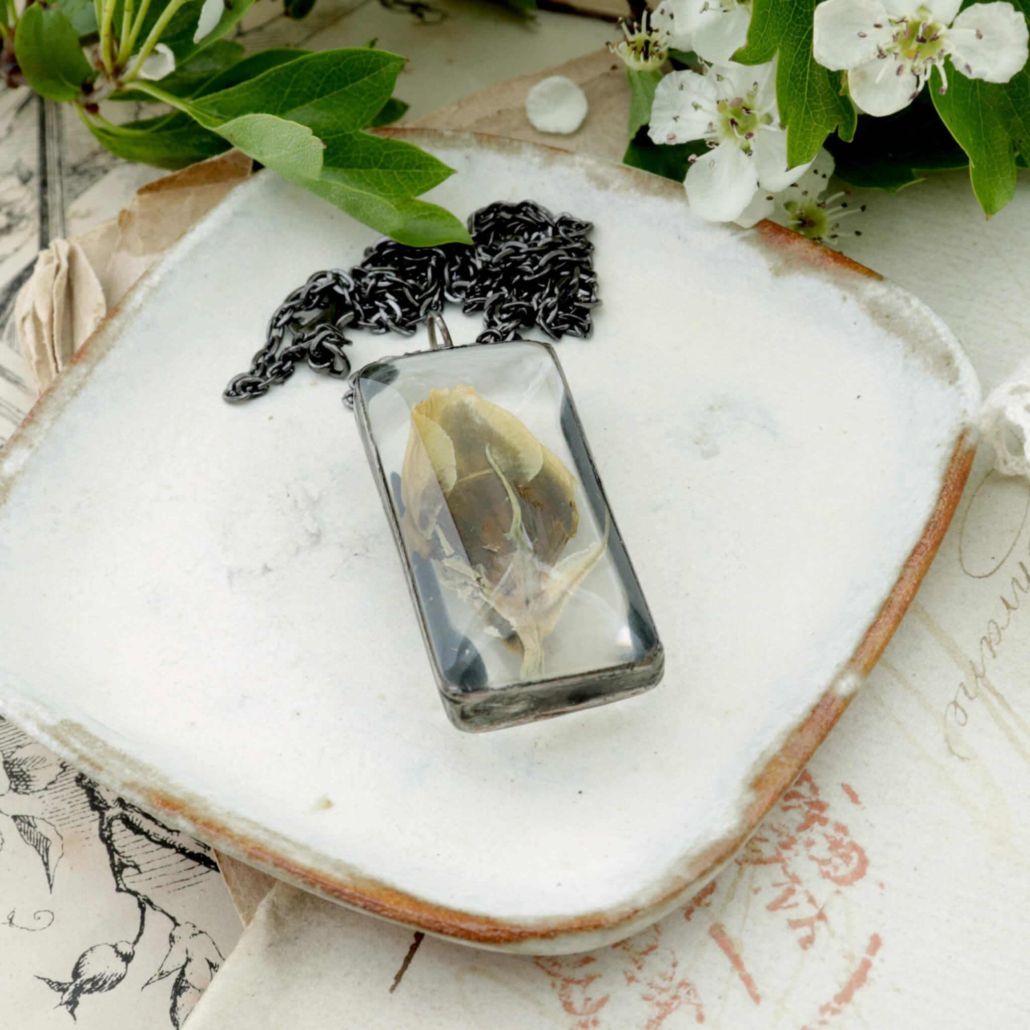 Flower bud framed in glass with solder lying on a white dish