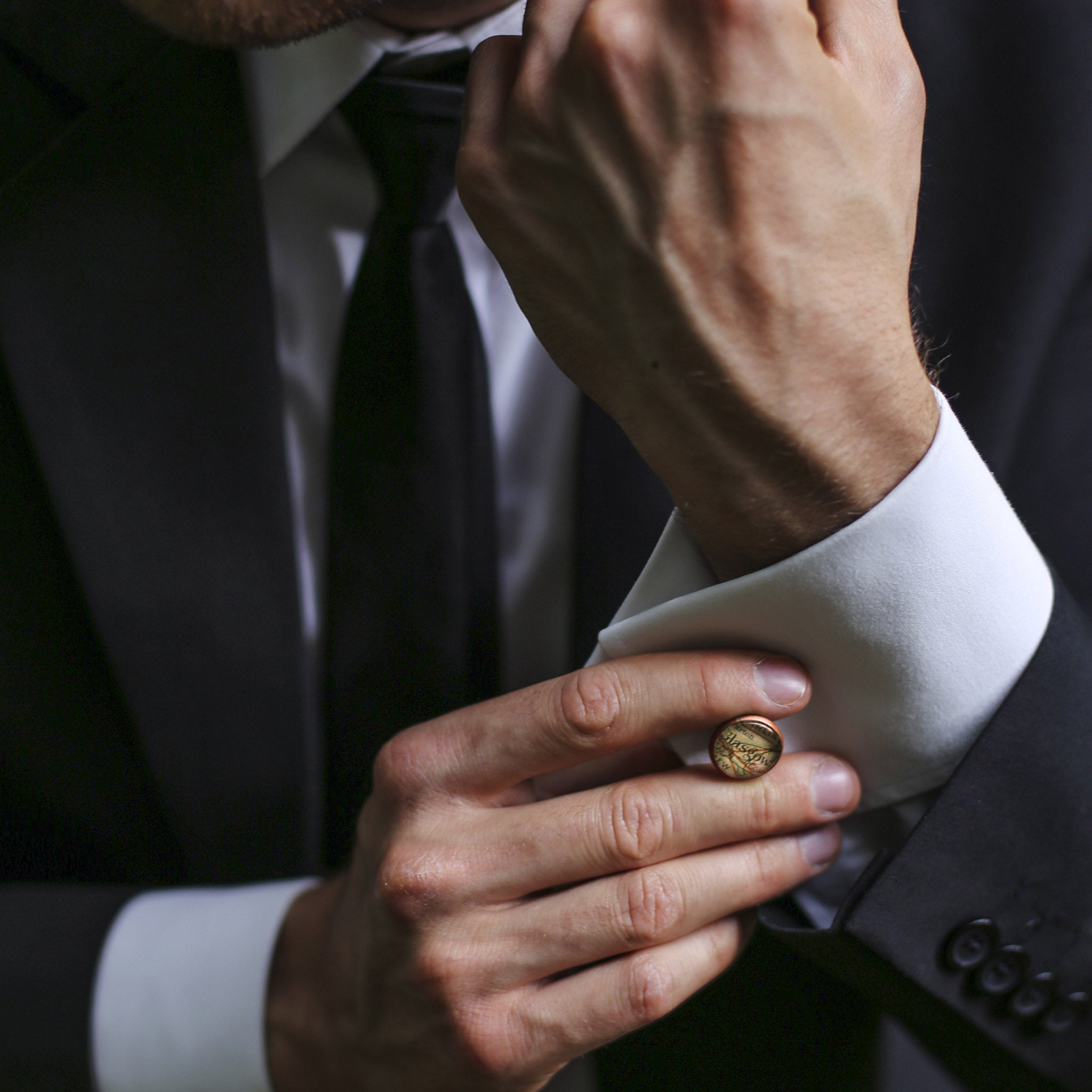 Man putting cufflinks into his shirt cuffs