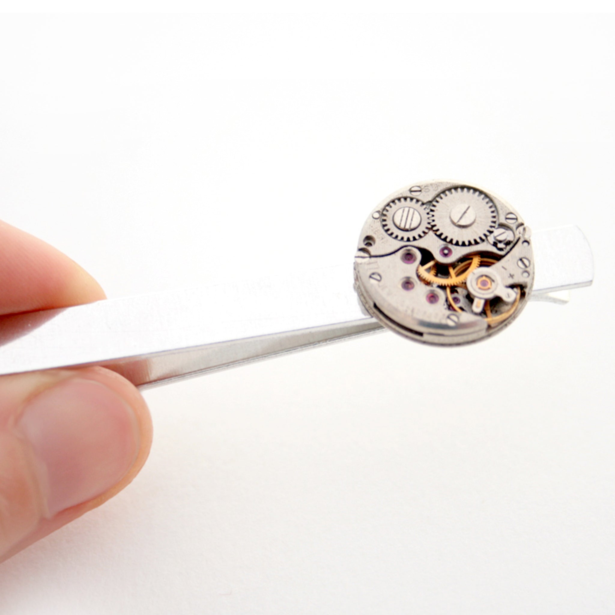 Hand holding Steampunk Tie Clip featuring antique watch movement