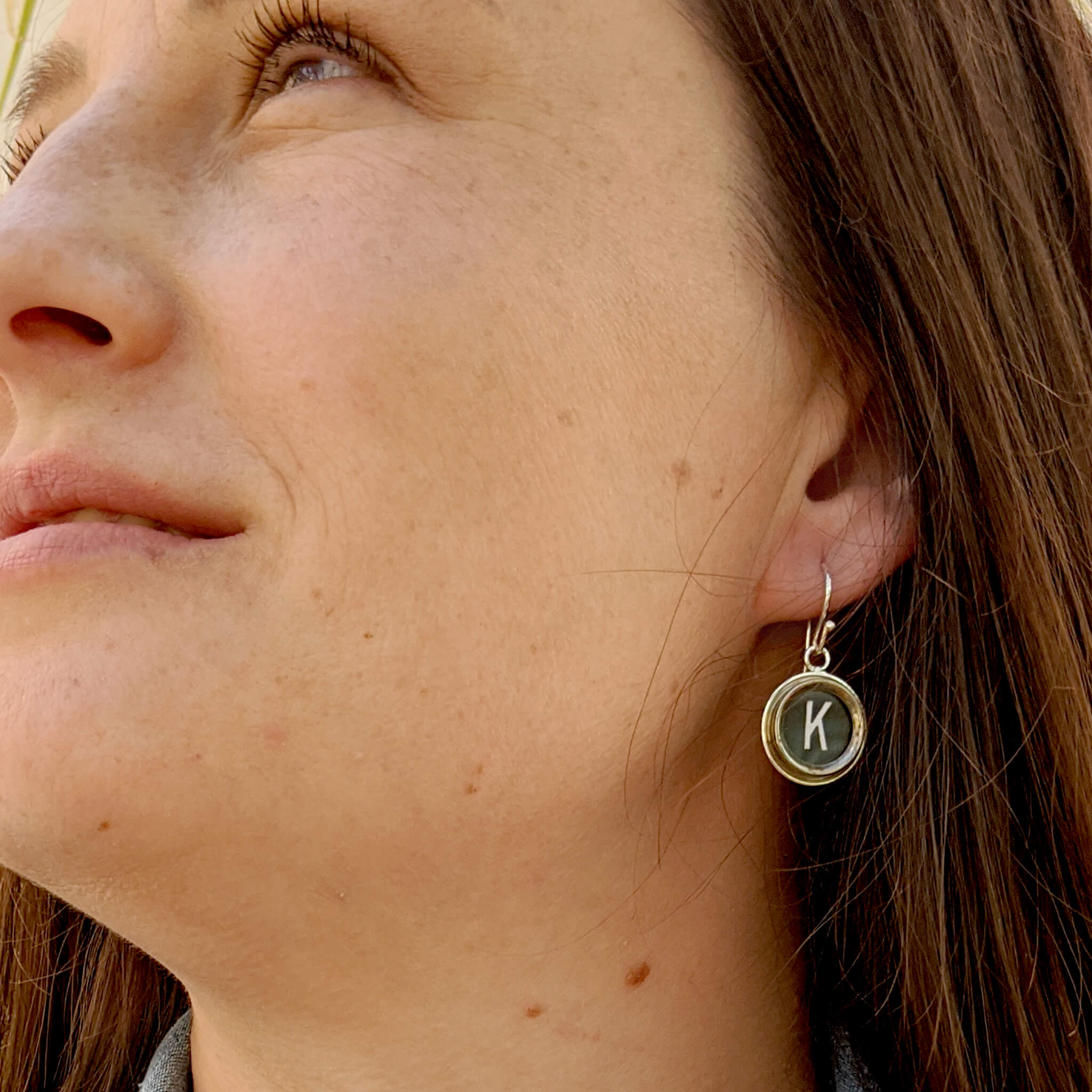Woman wearing typewriter key earrings with letter K