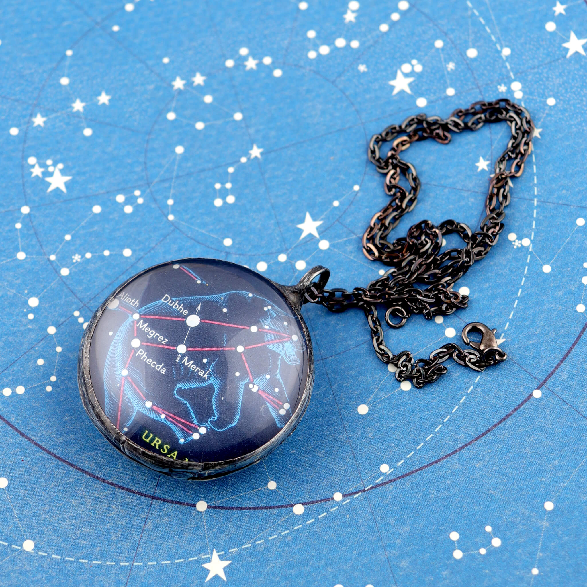 Ursa Major stained glass necklace lying on celestial stationery