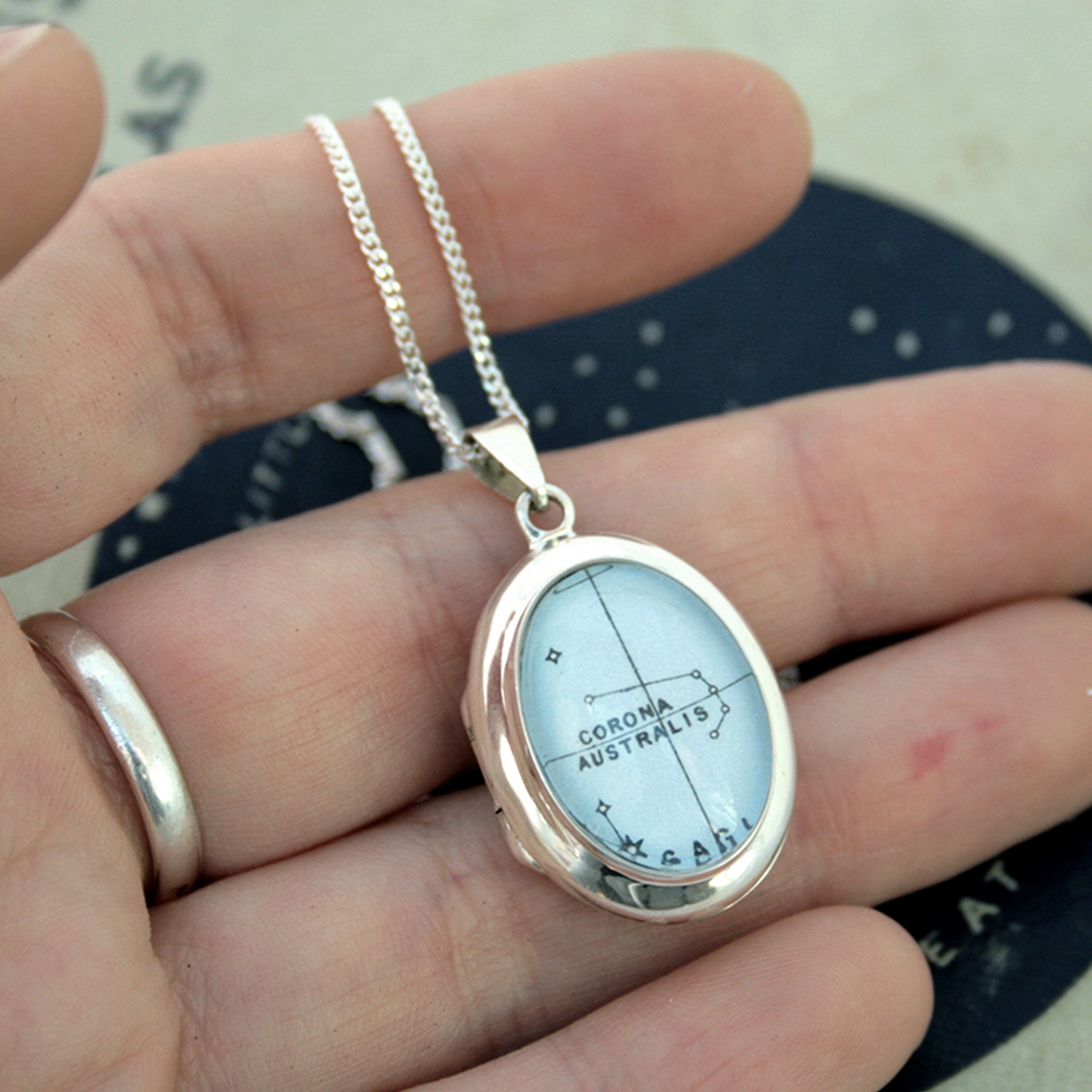 Hold in hans Sterling Silver locket necklace featuring Corona Australis star constellation