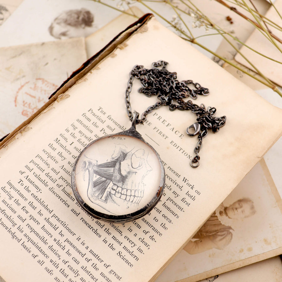 skull illustration stained glass necklace lying on an old book