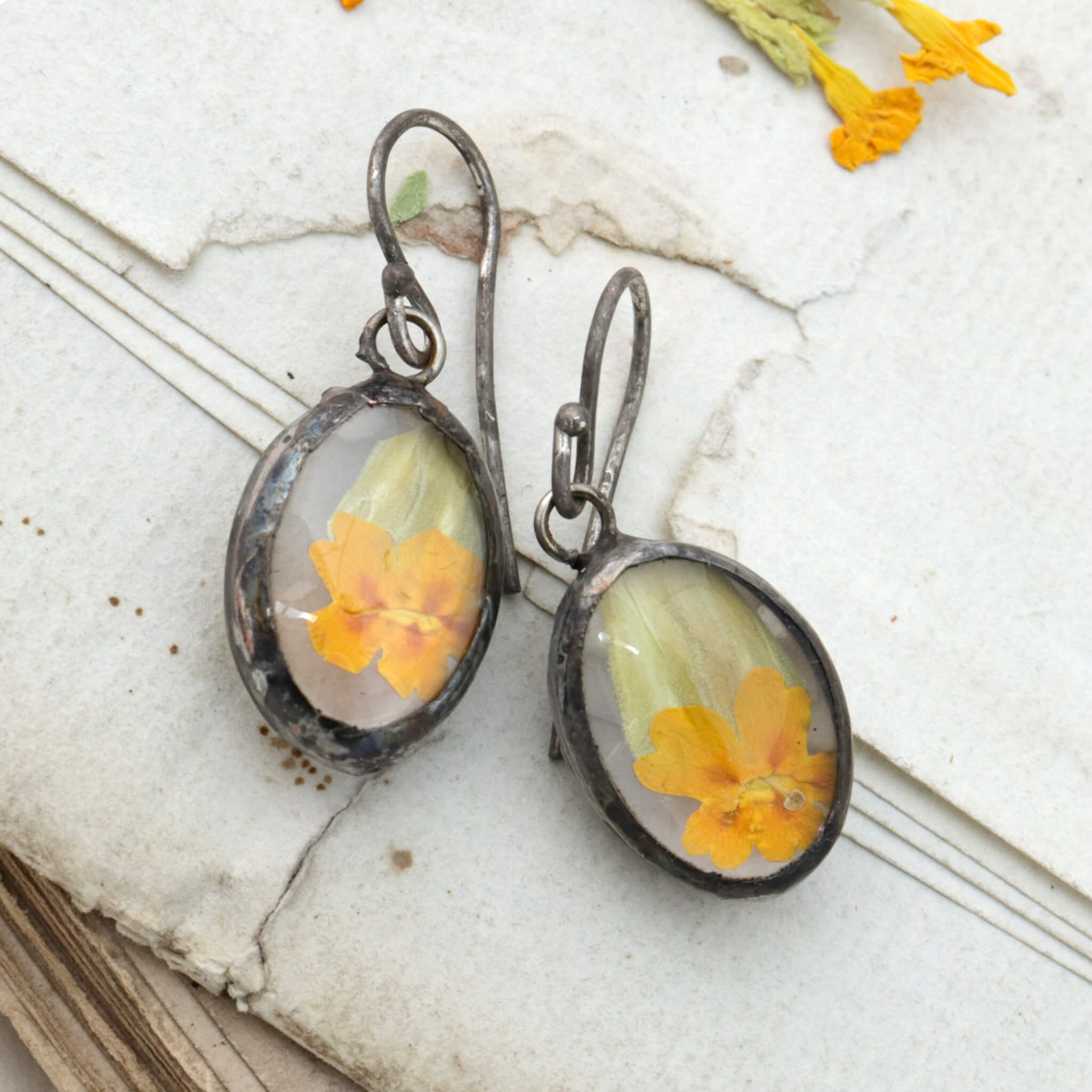 Primroses in soldered glass earrings lying on an old letter