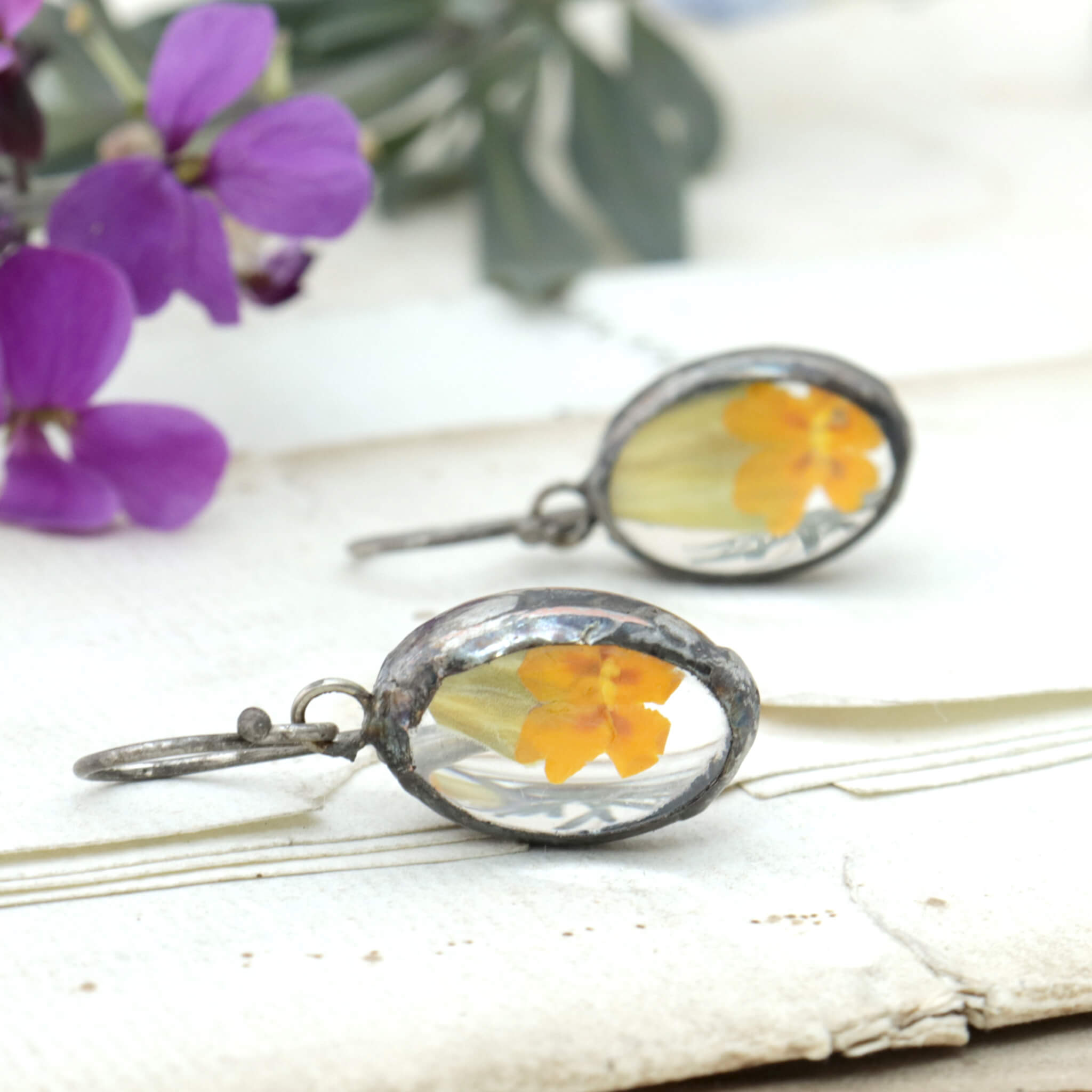 Primroses in soldered glass earrings lying on an old letter