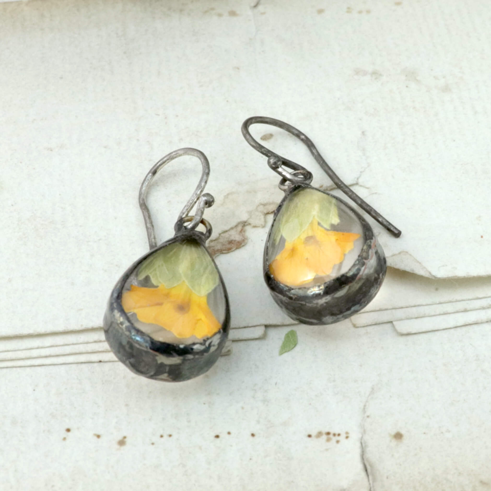 Primroses in soldered glass earrings lying on an old letter