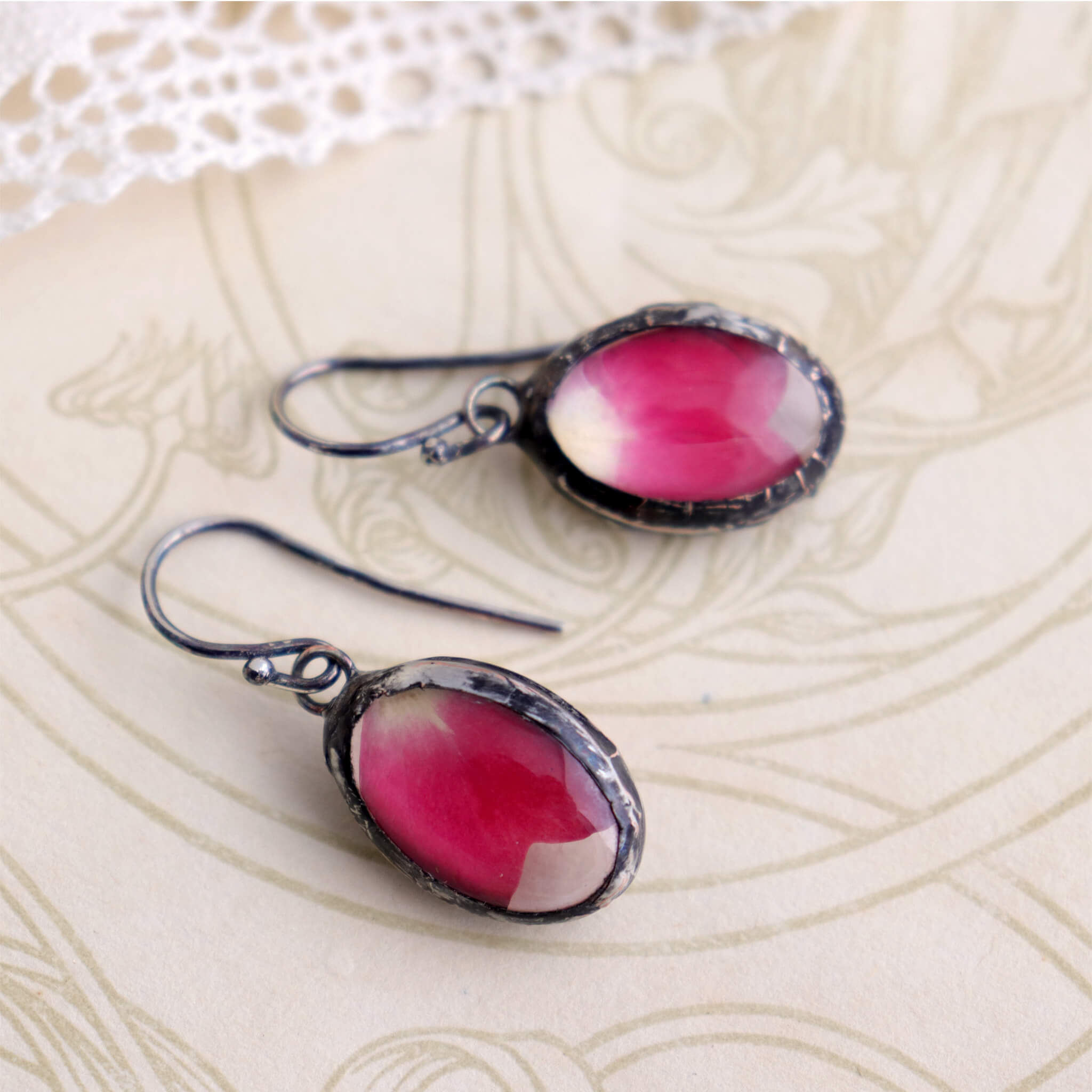 Rose petal earrings lying on an old book