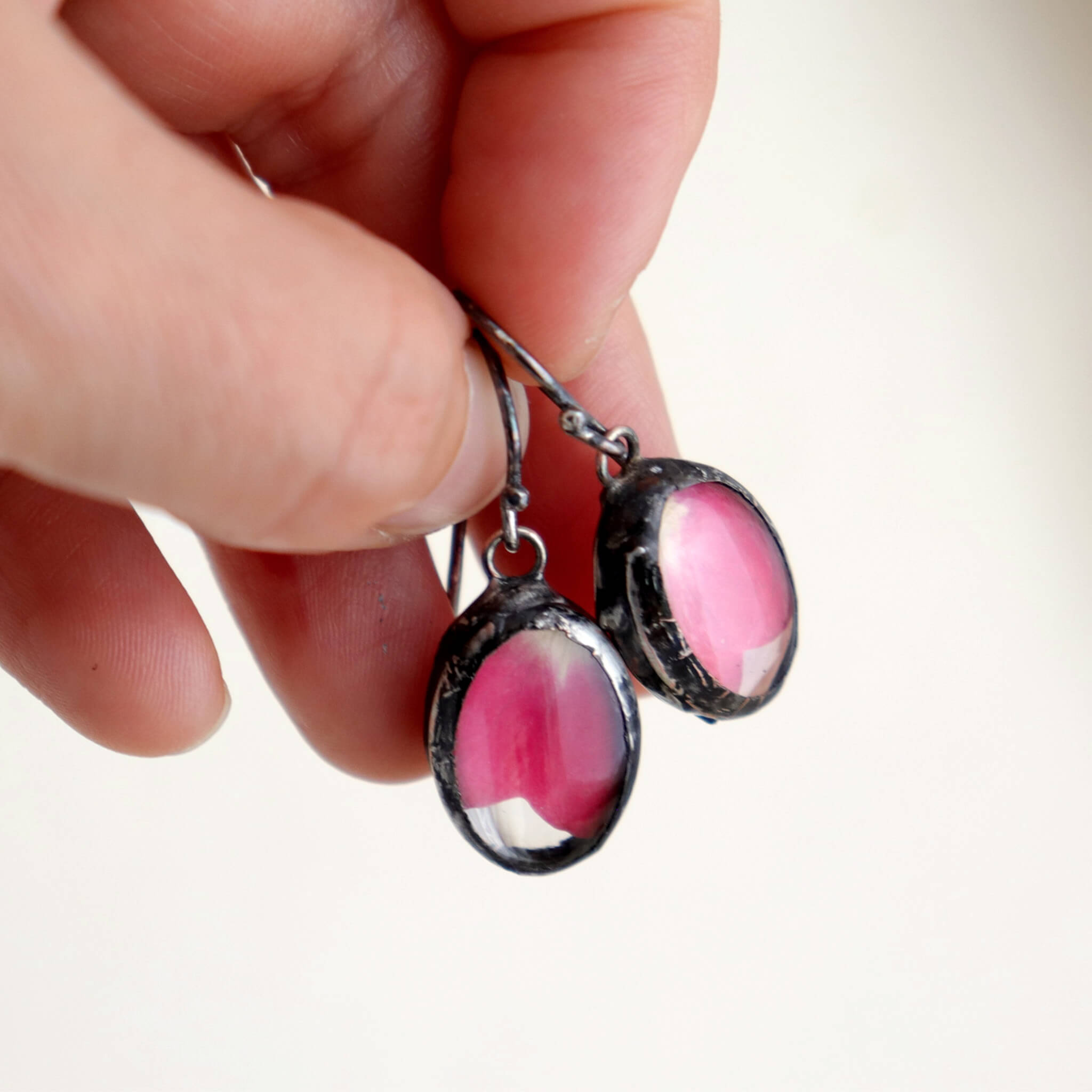 Hand holding Rose petal earrings in oval shape