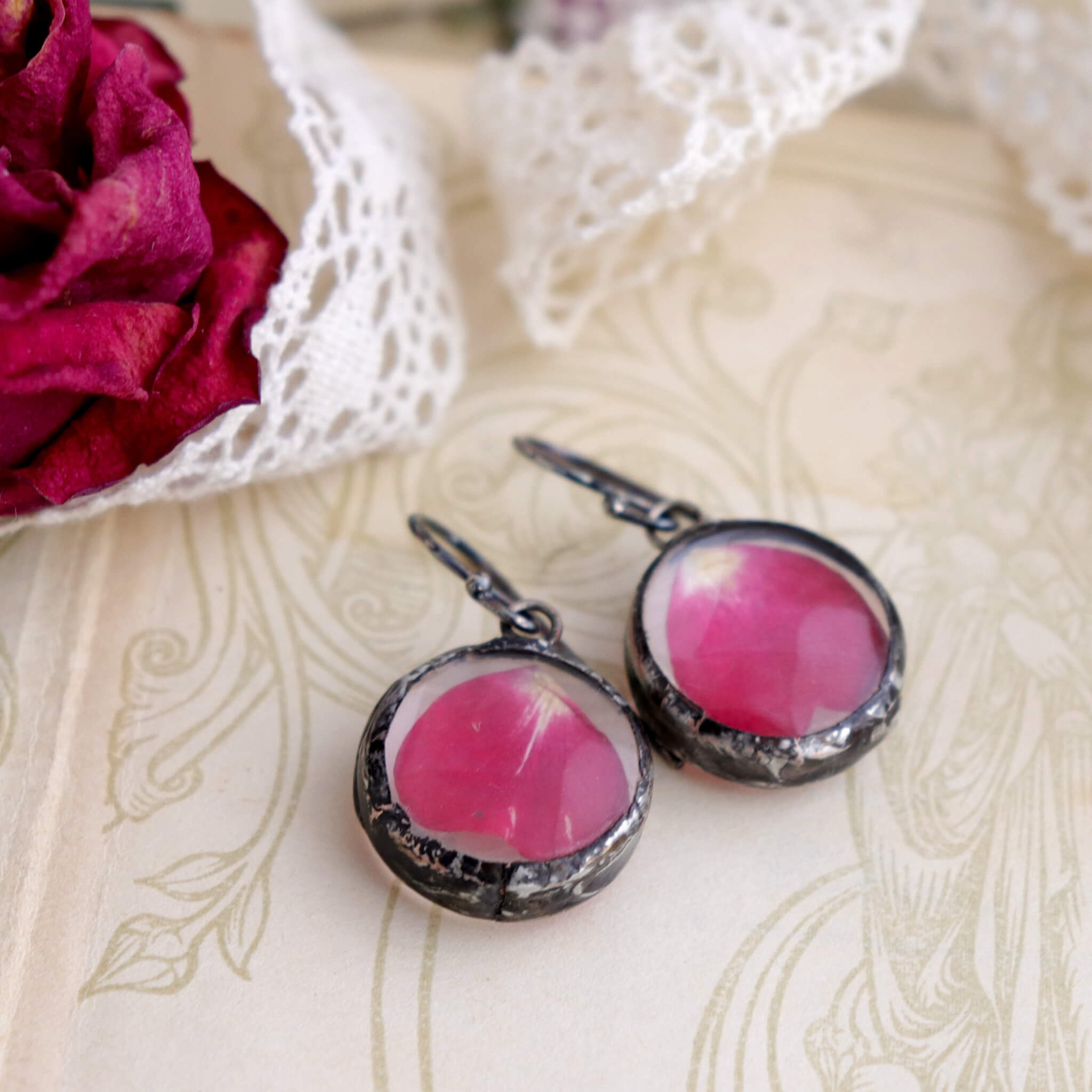 Rose petal earrings lying on an old book