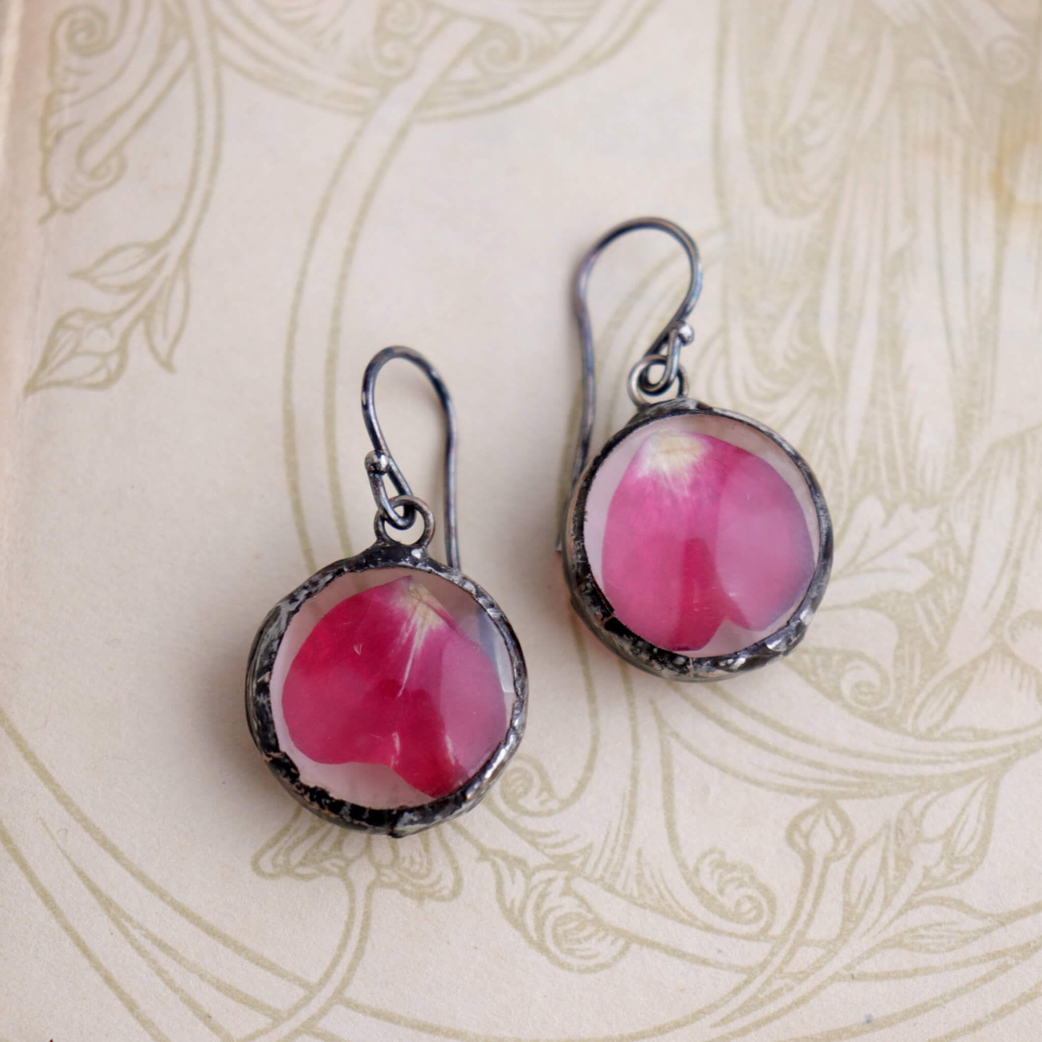 Rose petal earrings lying on an old book