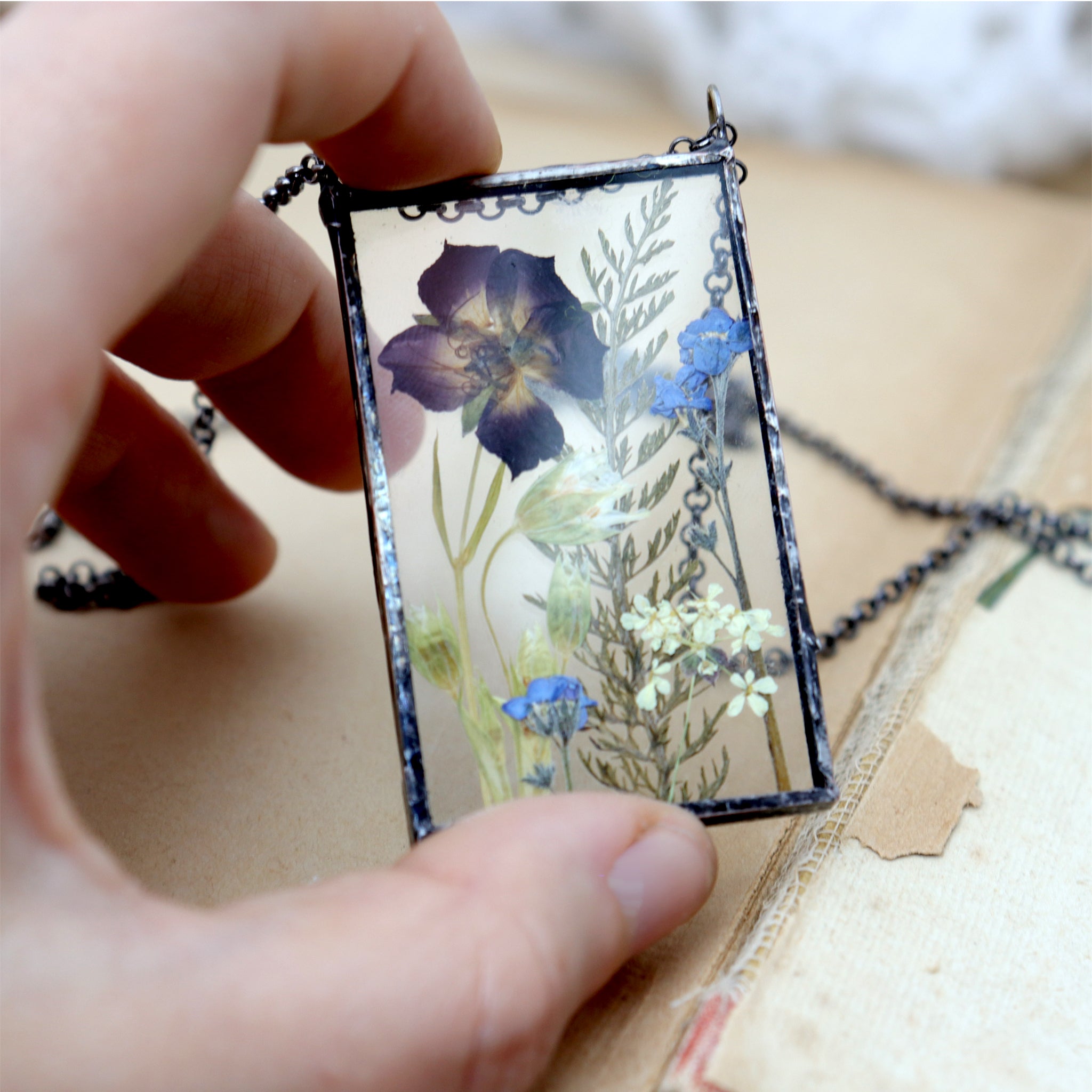 Hand holding pressed meadow flower necklace