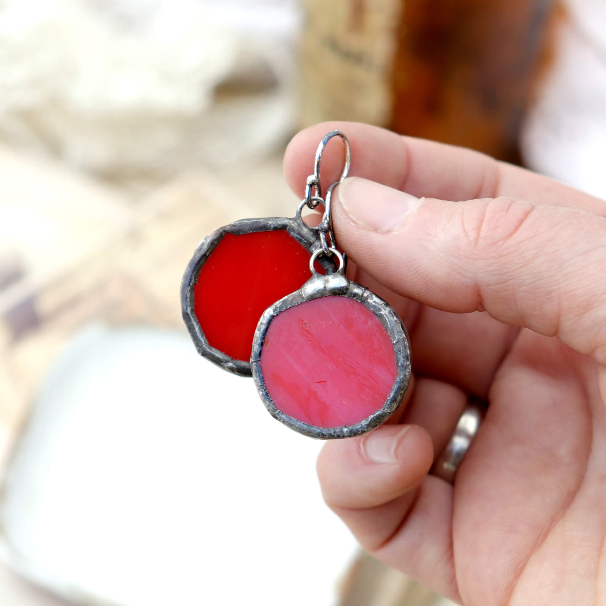 hand holding circles of glass in red colour turned into stained glass earrings
