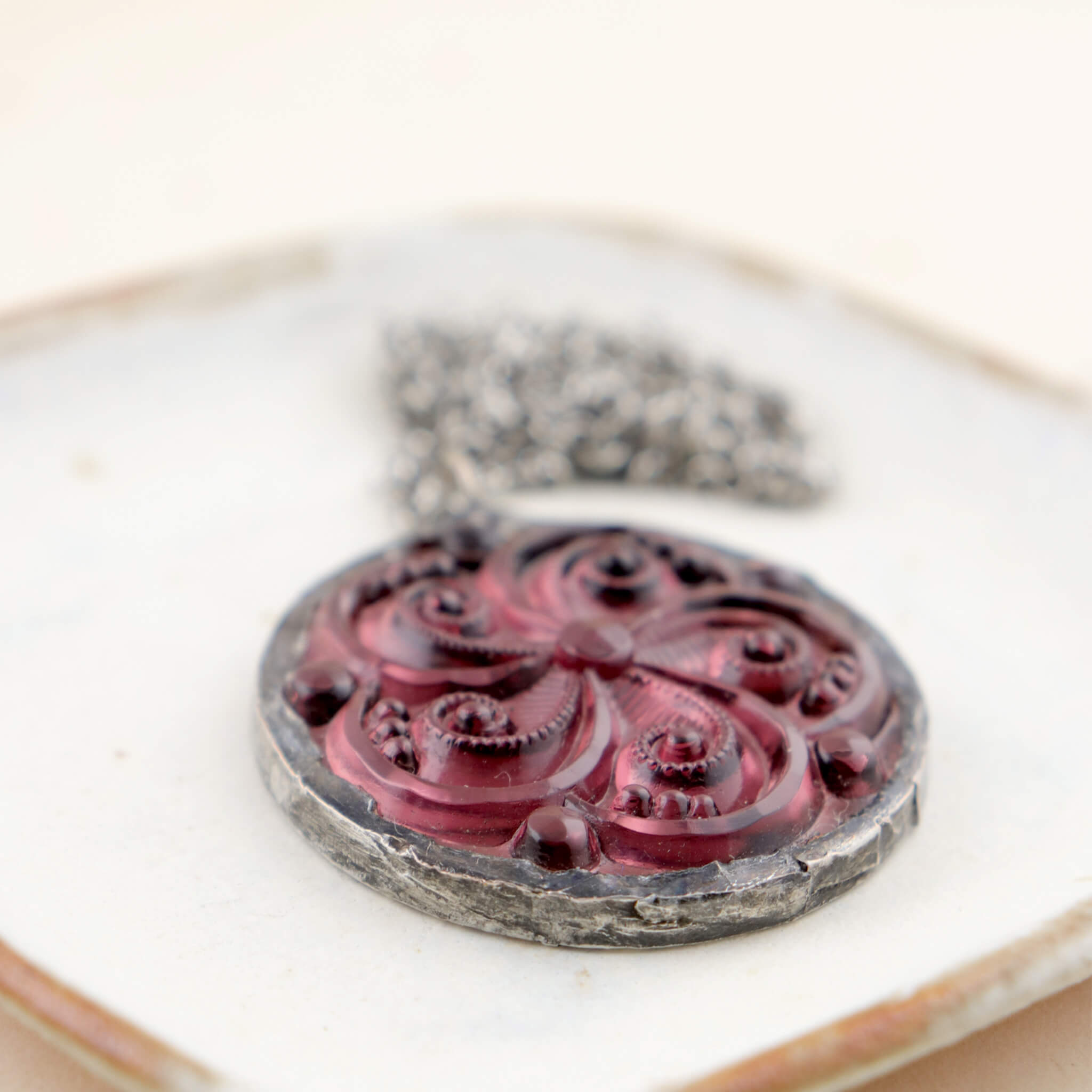 Amethyst swirl glass rondelle framed into stained glass necklace lying on a white dish