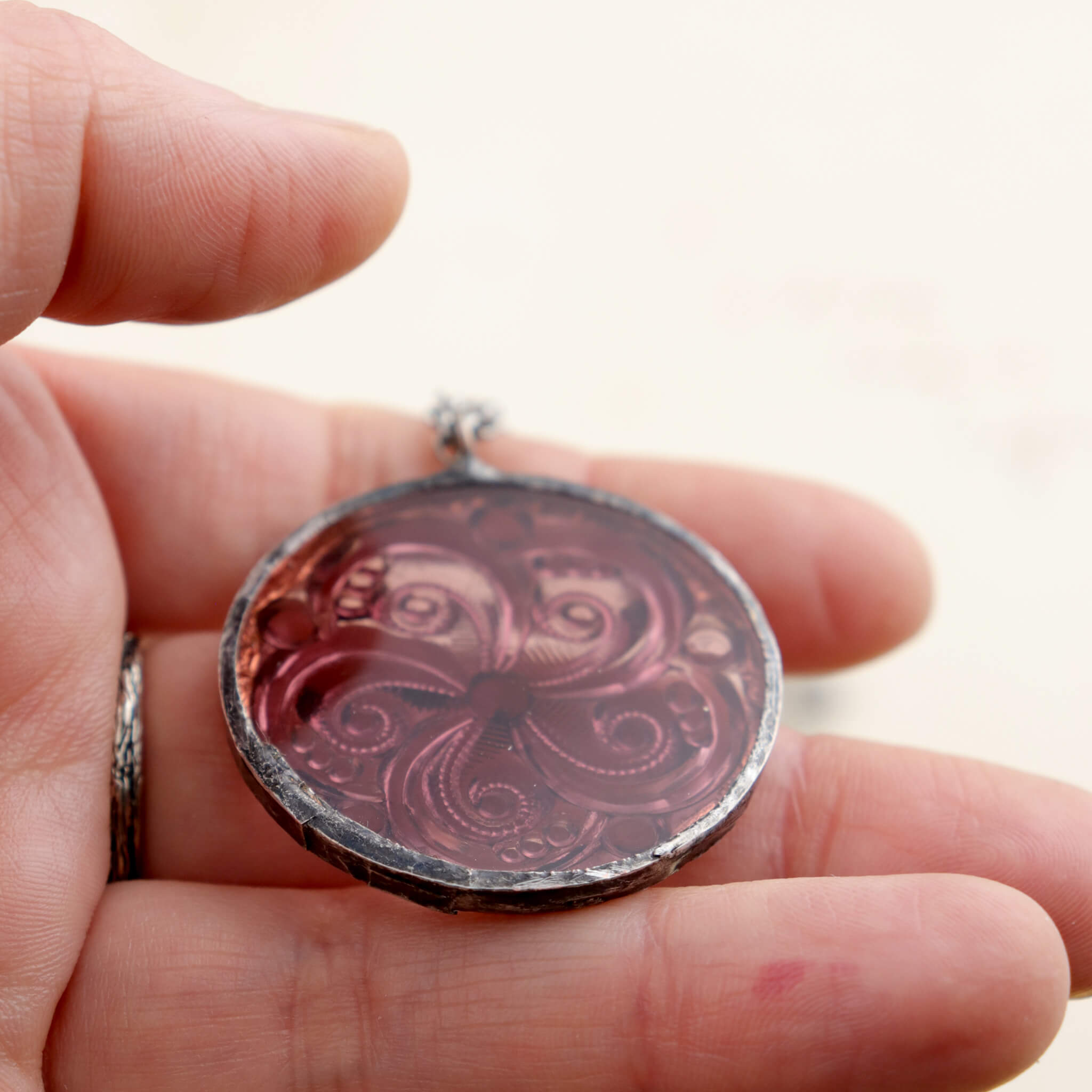 Amethyst swirl glass rondelle framed into stained glass necklace lying on a hand