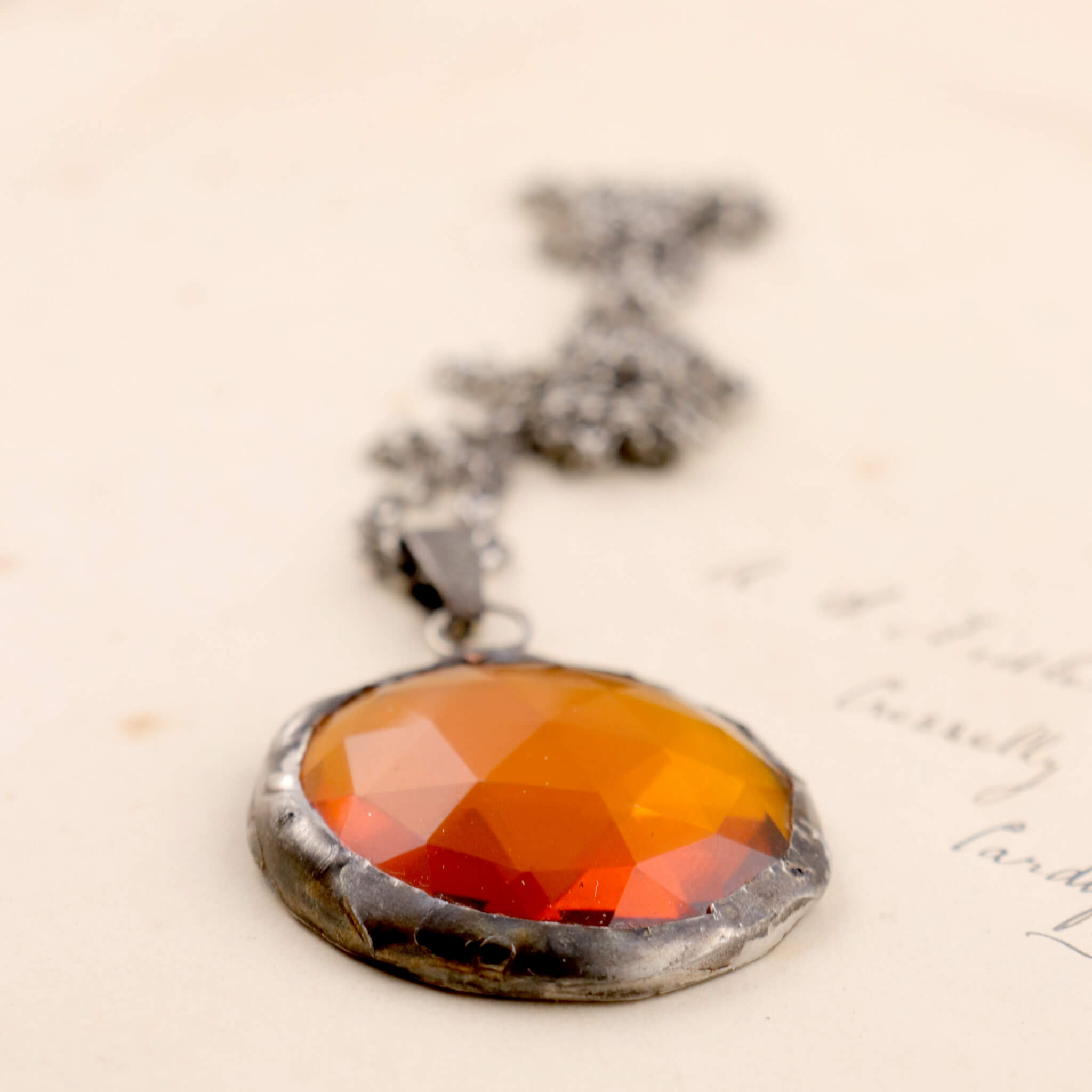 Faceted amber glass framed into necklace lying on an old letter
