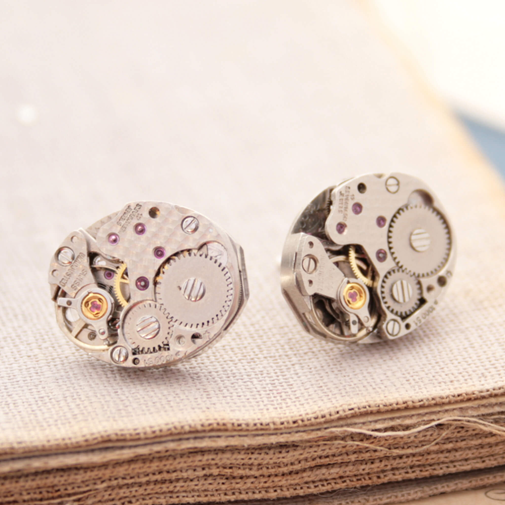 watch movements turned into stud earrings lying on an old book