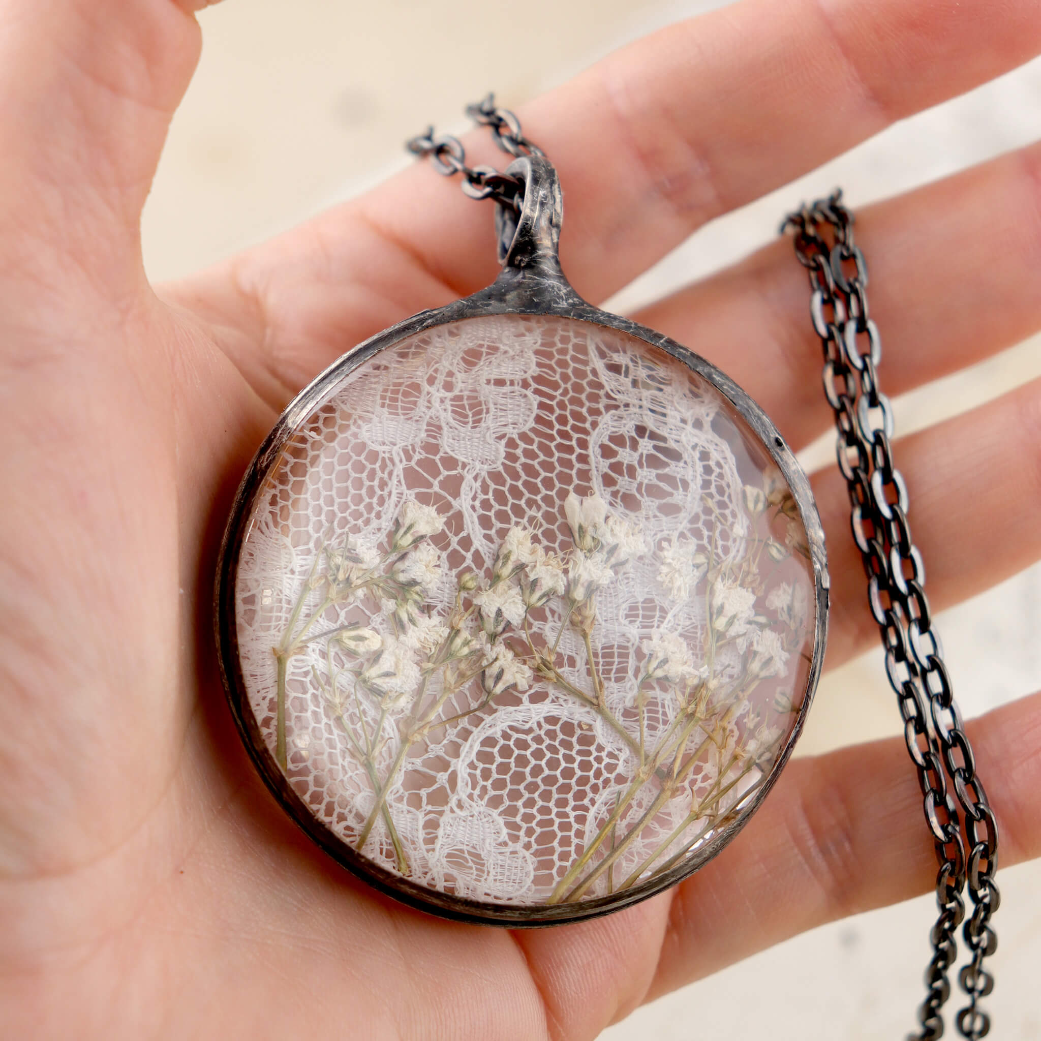 Hand holding glass necklace with gypsophila flowers 