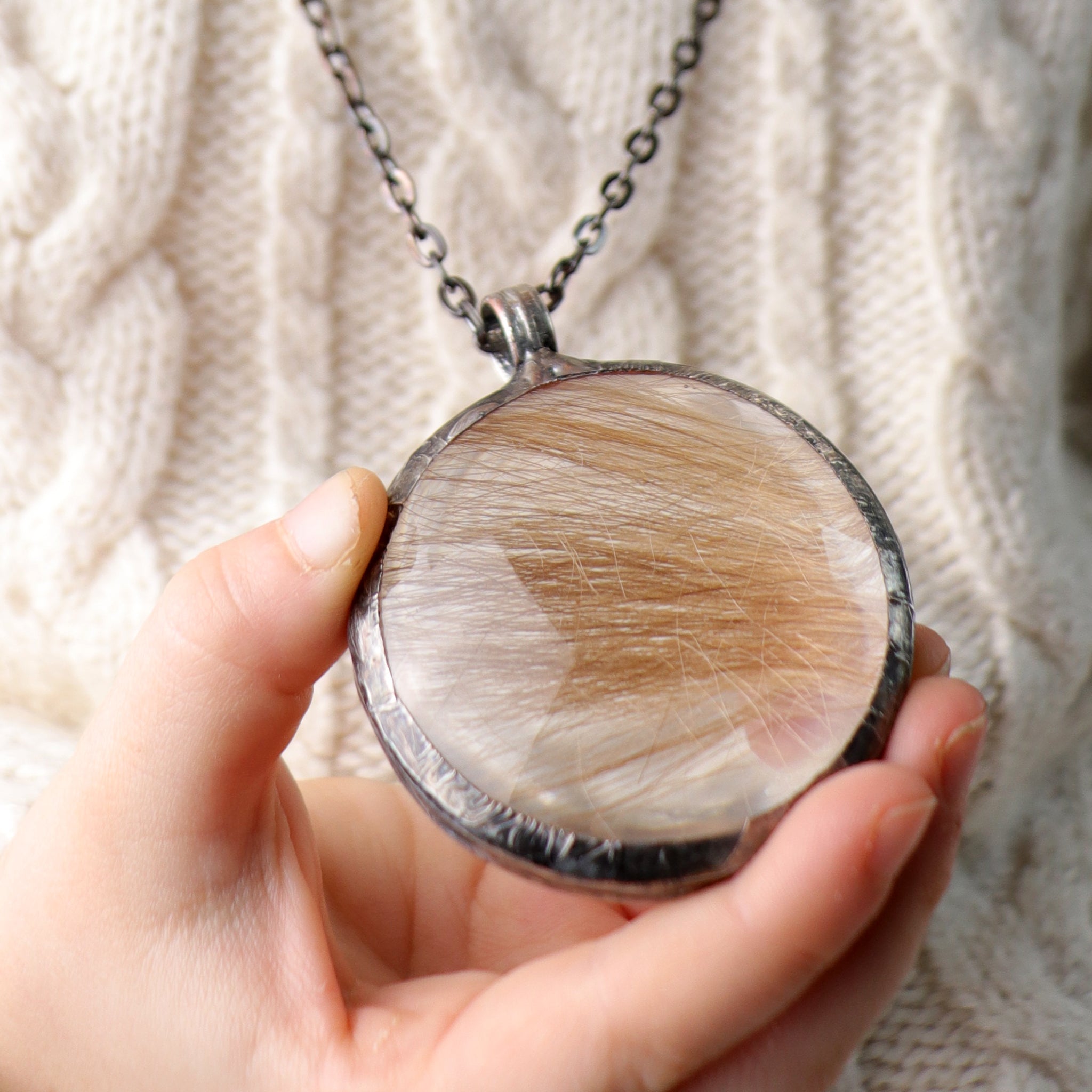 A girl holding memento hair necklace