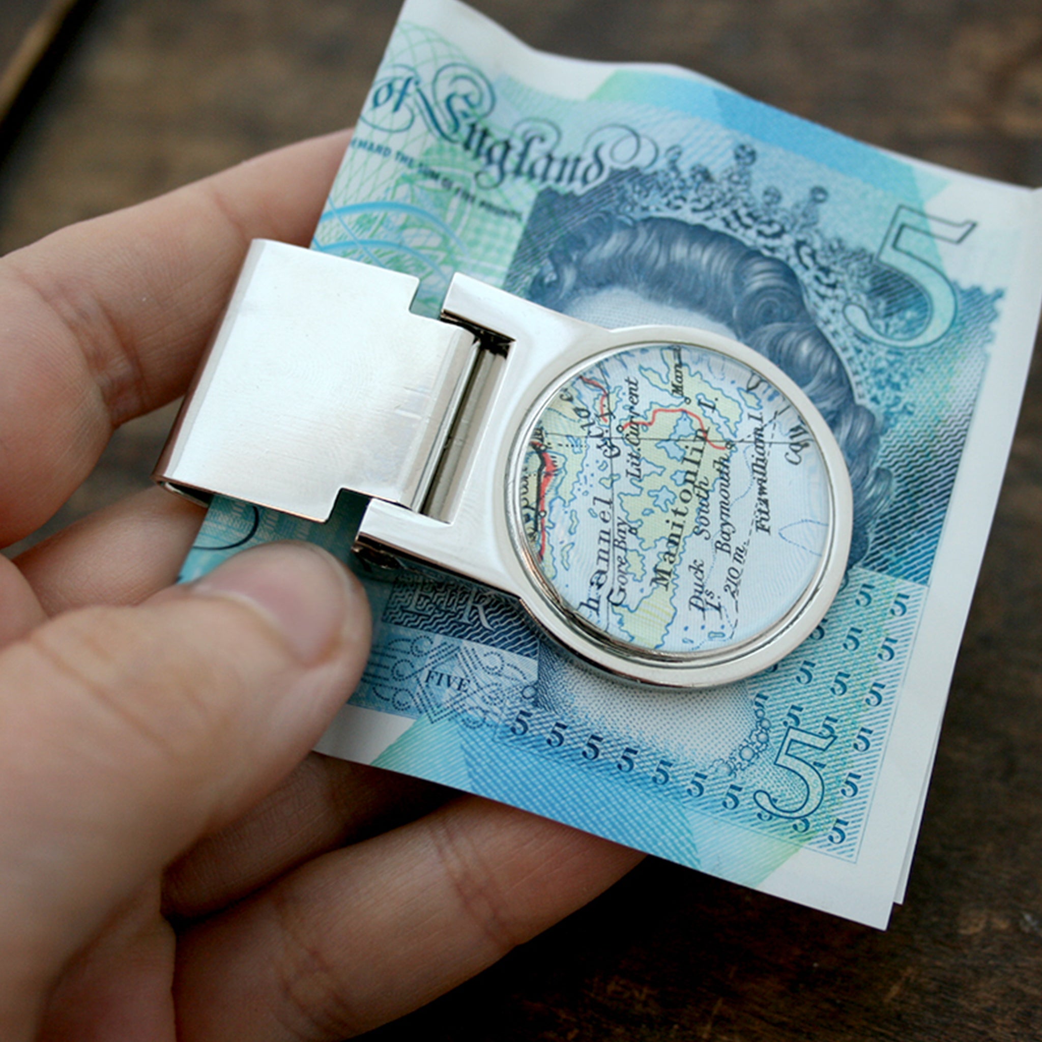 Hand holding money clip personalised with geographical map