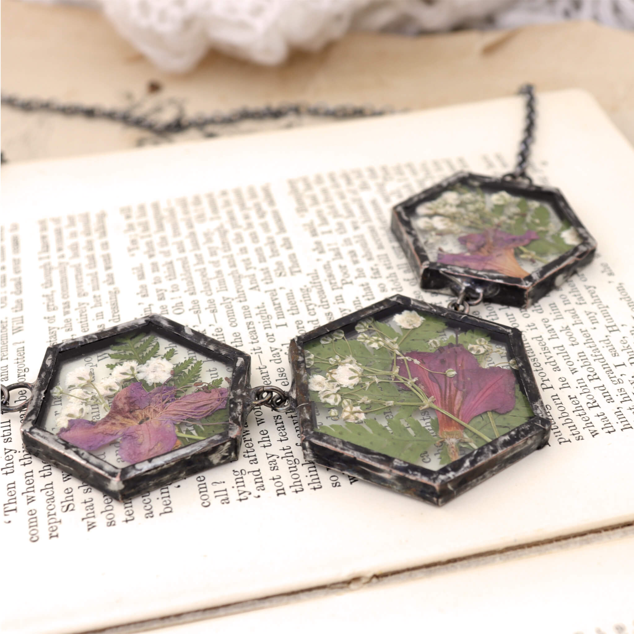  lying on an open book an azalea and fern three glass panel necklace