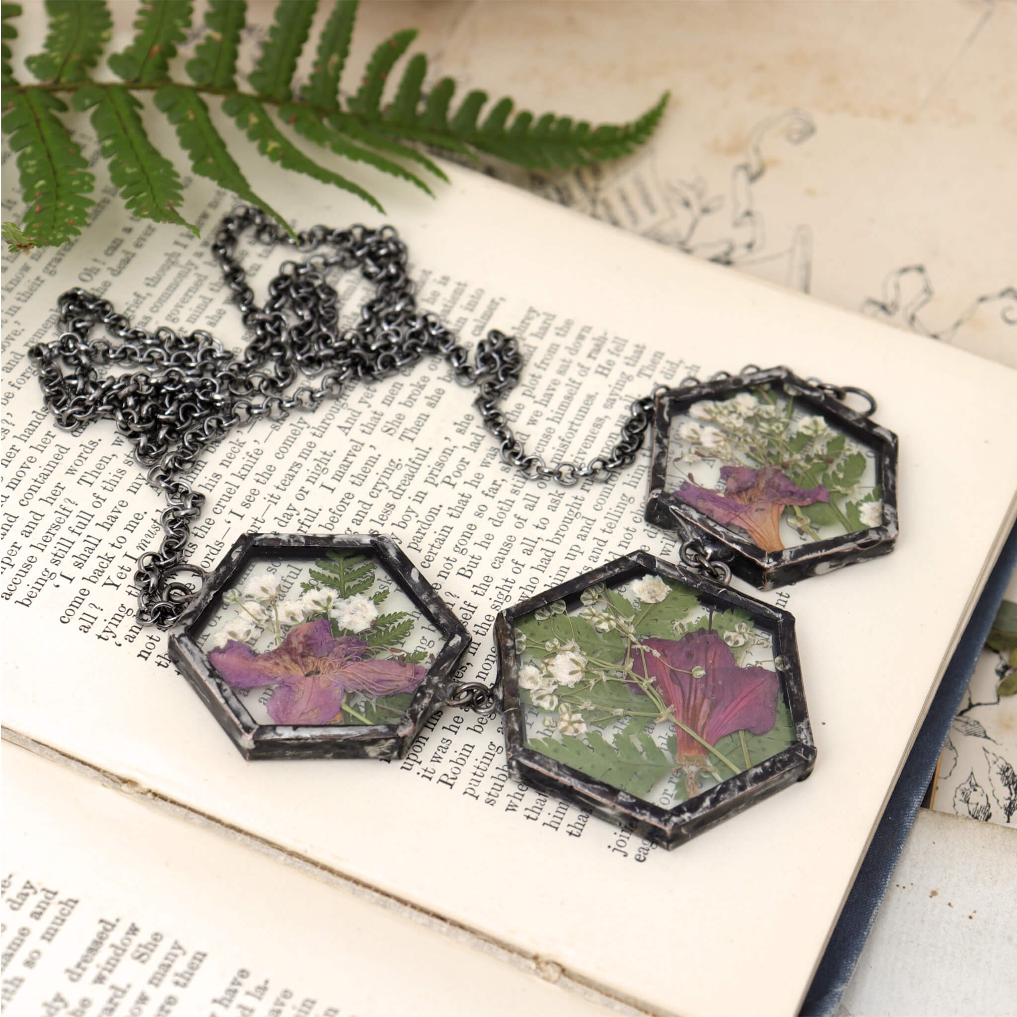  azalea and fern three glass panel necklace lying on an open book