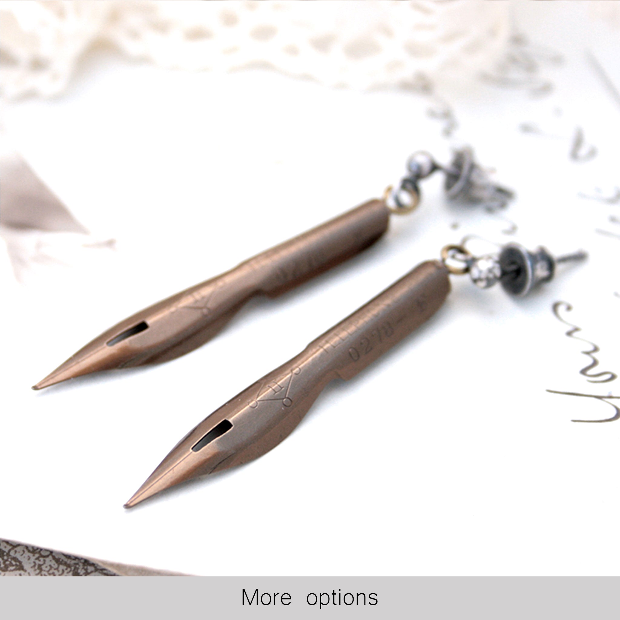 bronze earrings made of real pen nibs lying on an old photograph