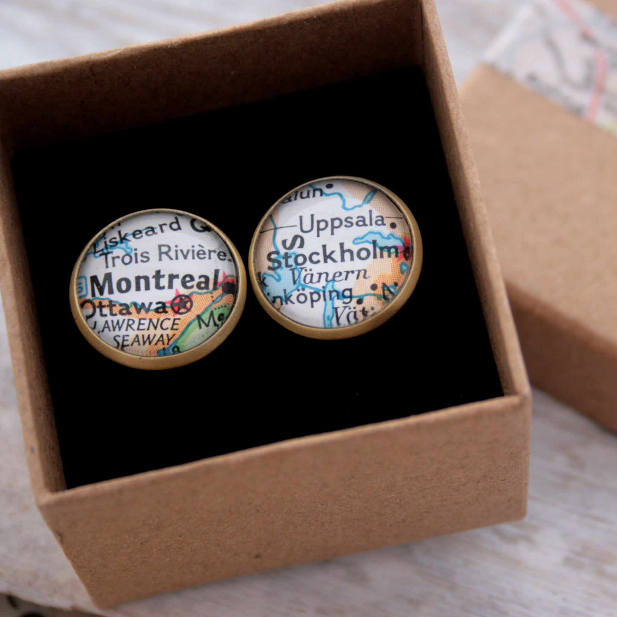 Personalised map cufflinks in brushed bronze color featuring maps of Stockholm and Montreal in a box