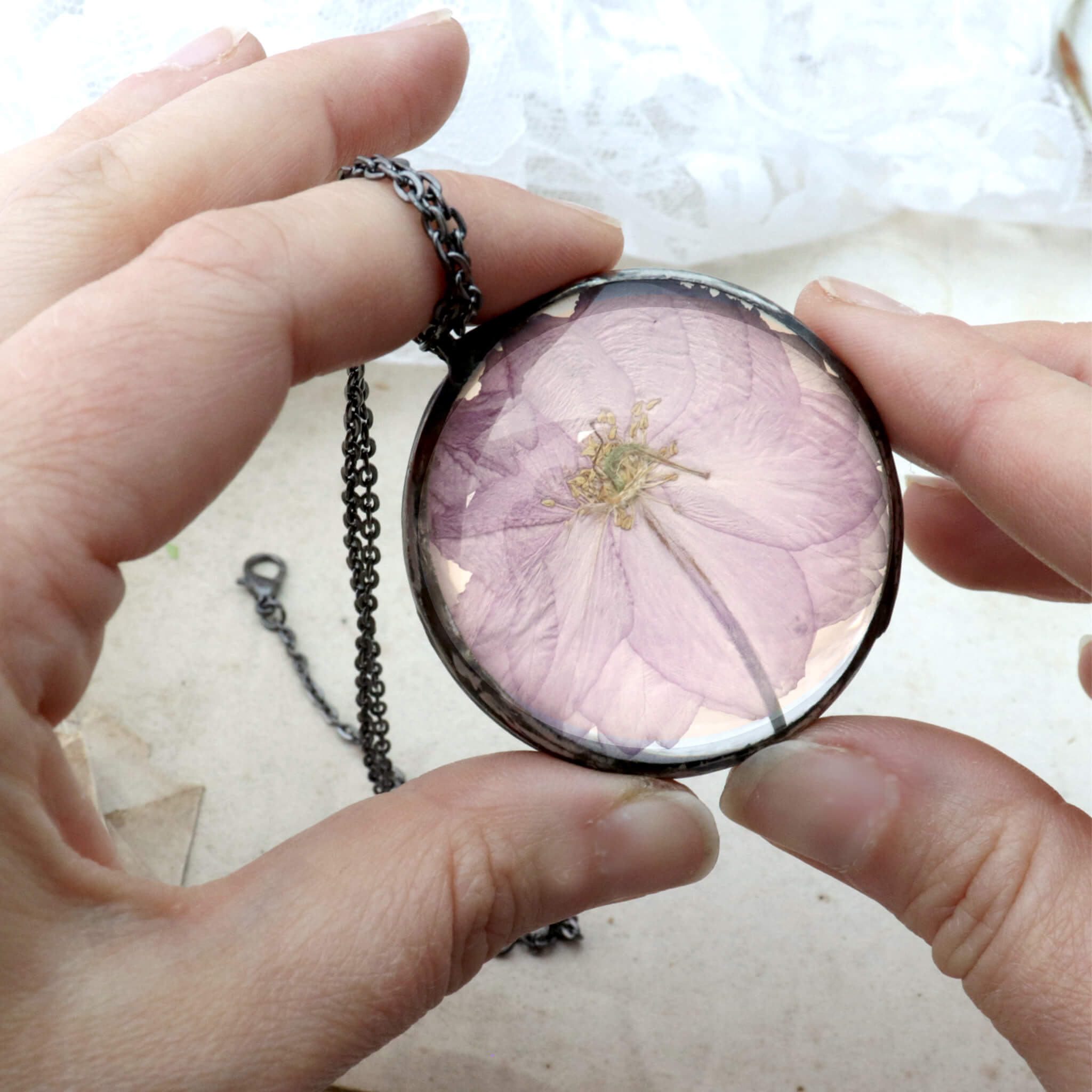 Round cherry blossom necklace being hold in hands