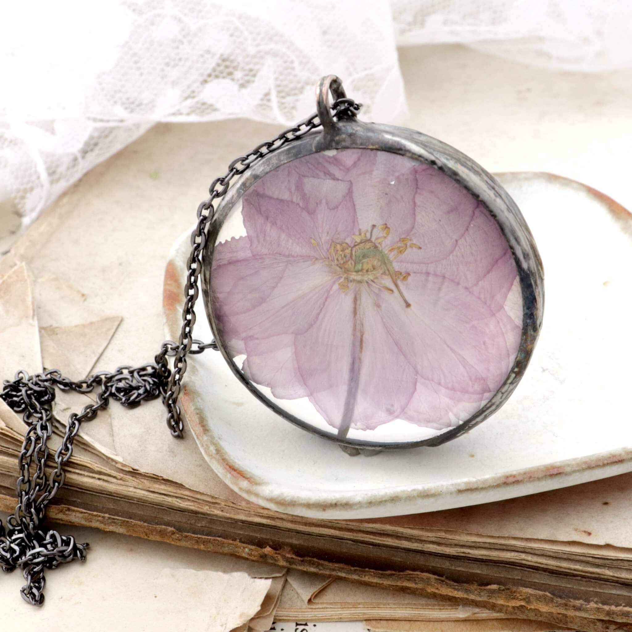 Round cherry blossom necklace standing on the edge on an old book