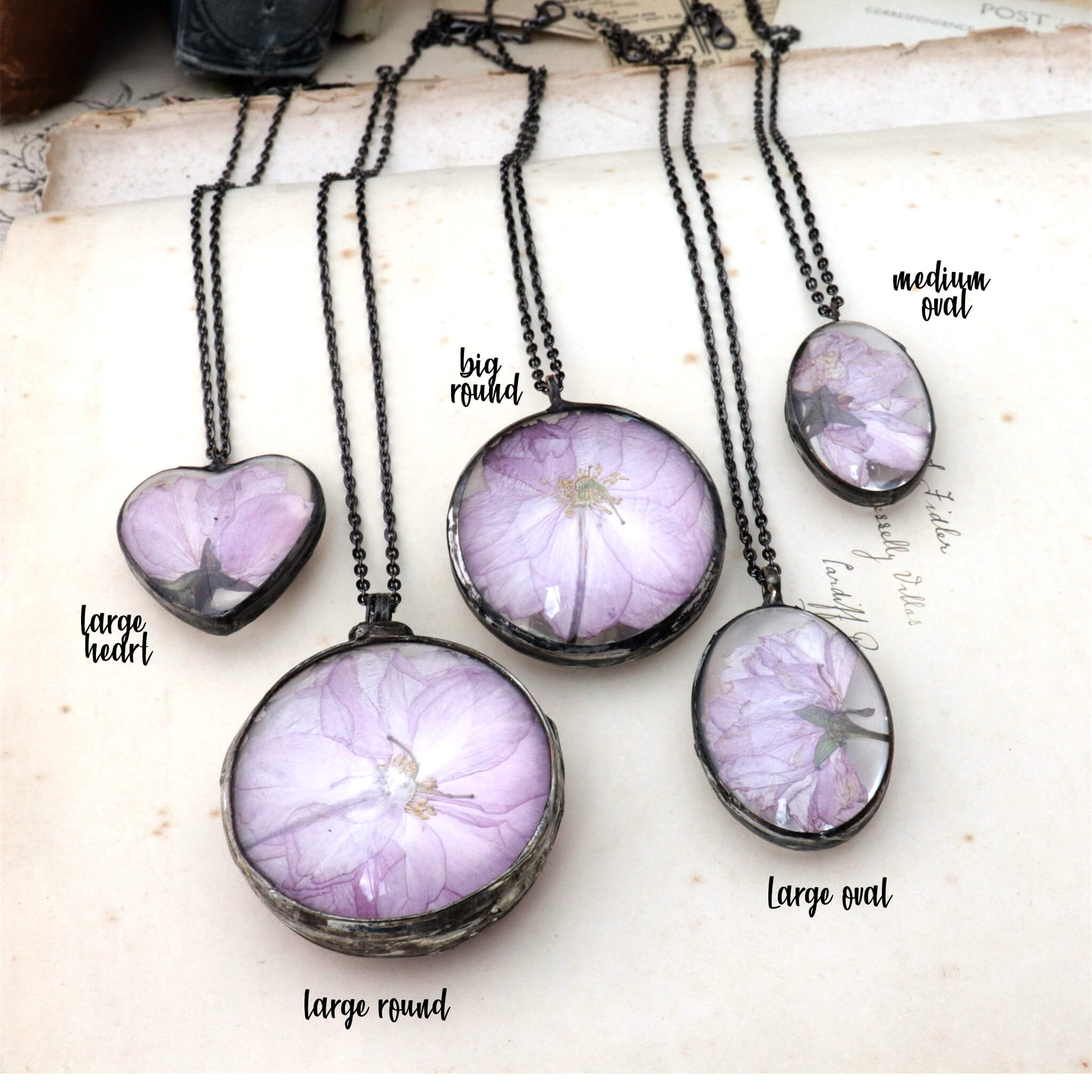 Five cherry blossom necklaces lying side by side on an old book