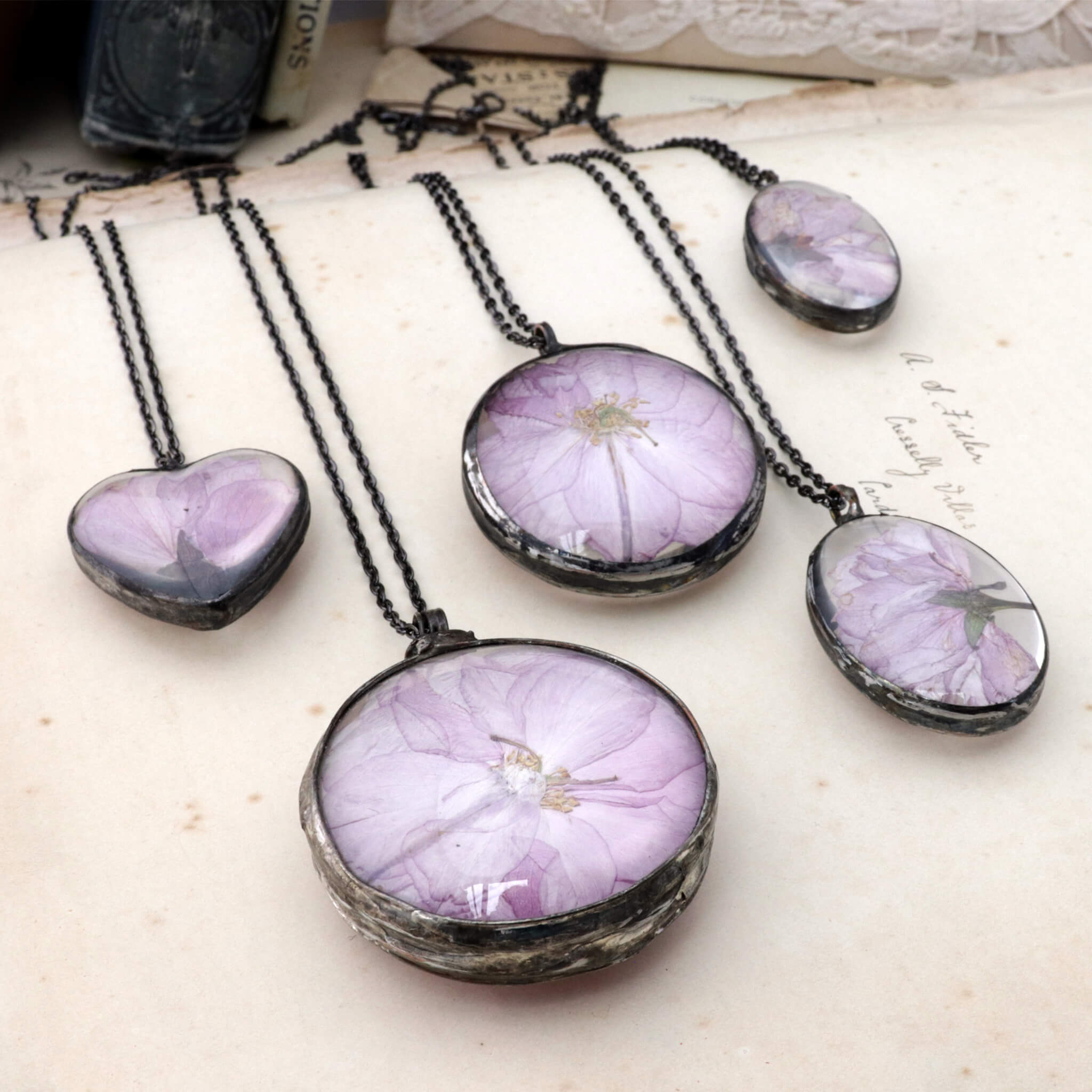 Five cherry blossom necklaces lying side by side on an old book