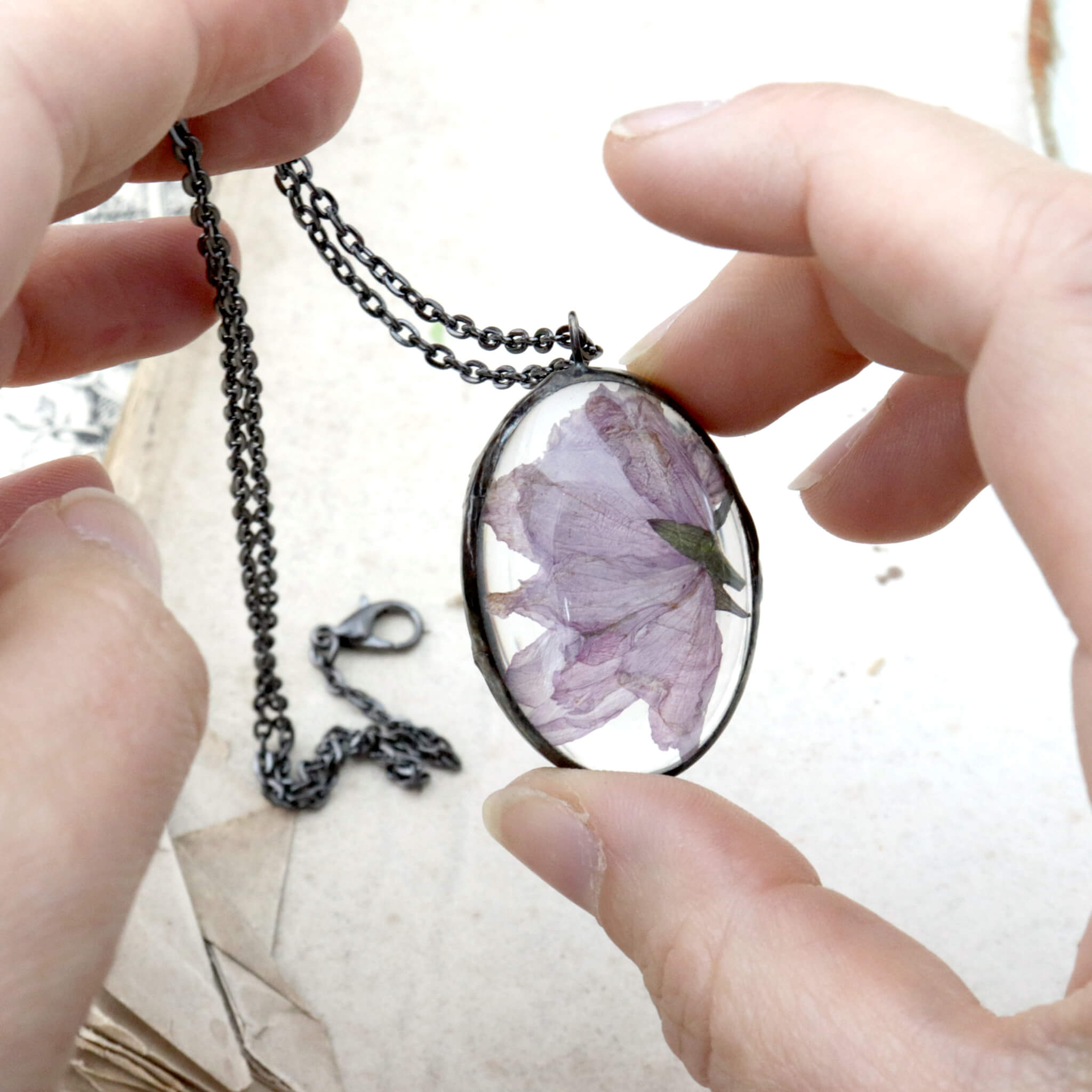 Oval cherry blossom necklace being hold in hands