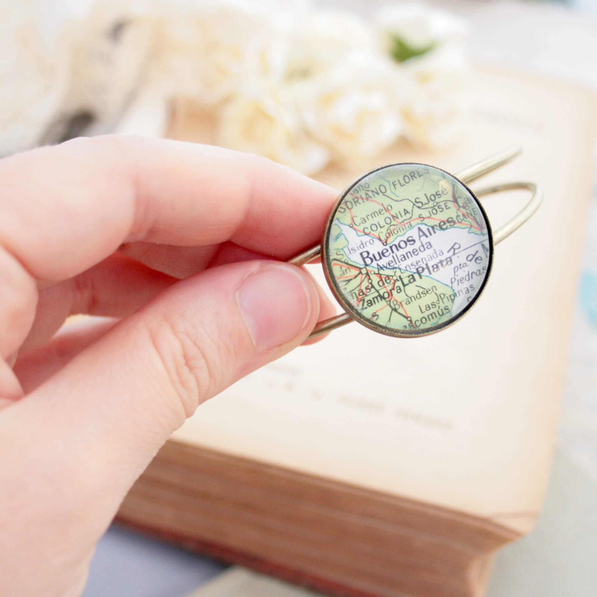 Hand holding Brushed bronze bangle bracelet with geographical map of Buenos Aires