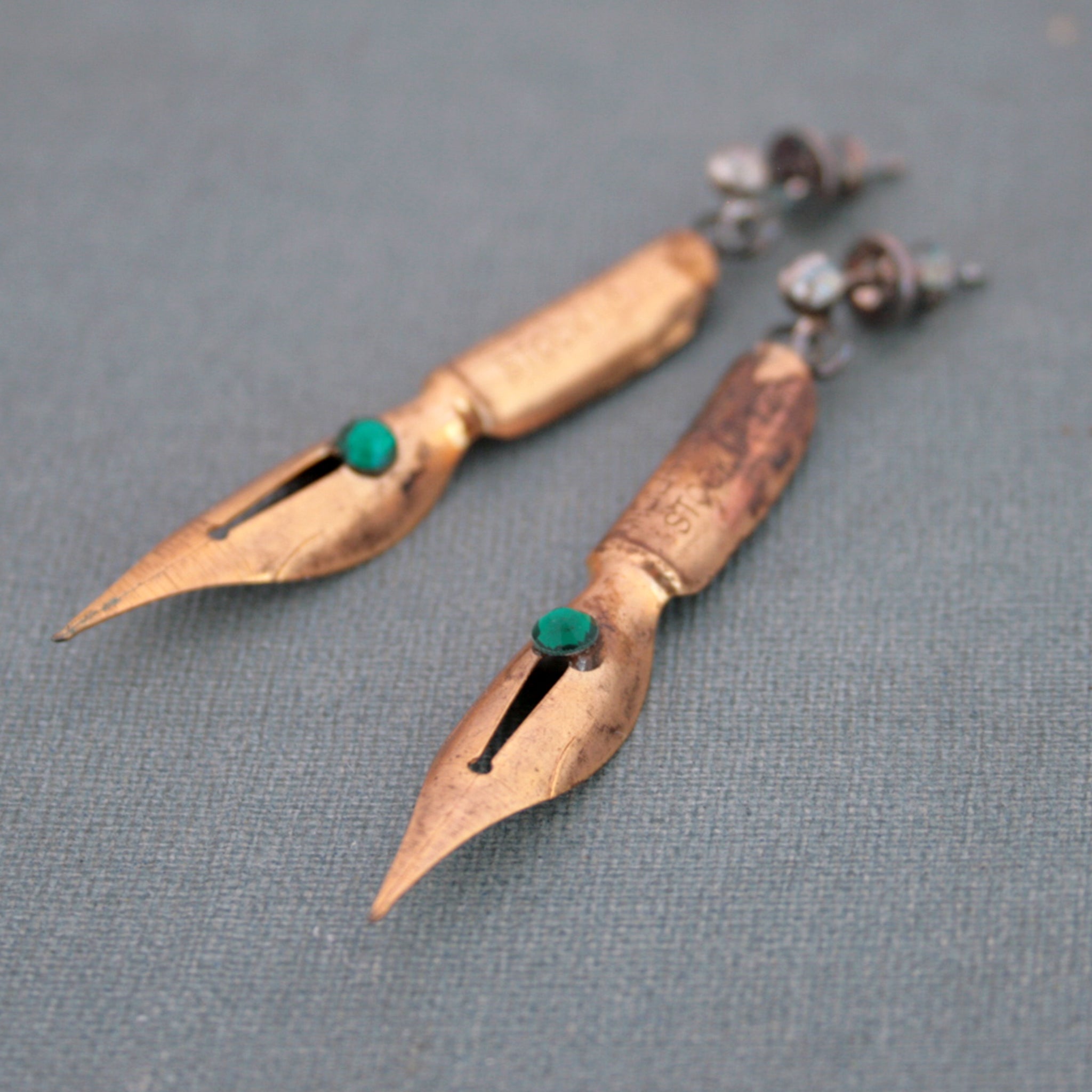 gold earrings made of real pen nibs lying on an old book