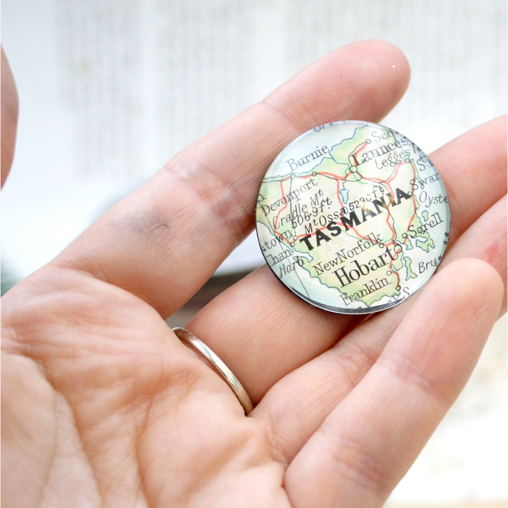 Hand holding a fridge magnet personalised with geographical map of custom locations