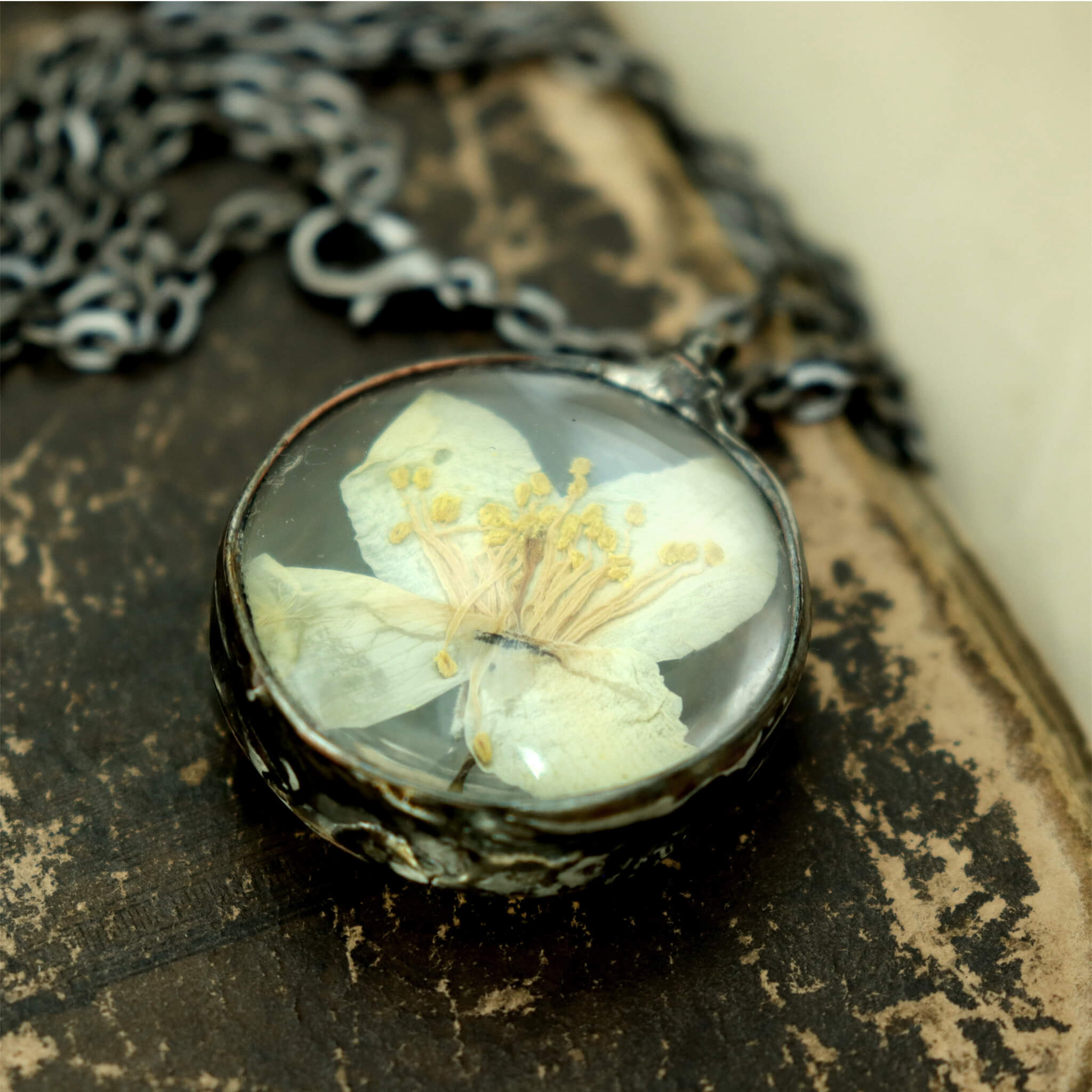 round jasmine necklace lying on a vintage brown covered and chipped book