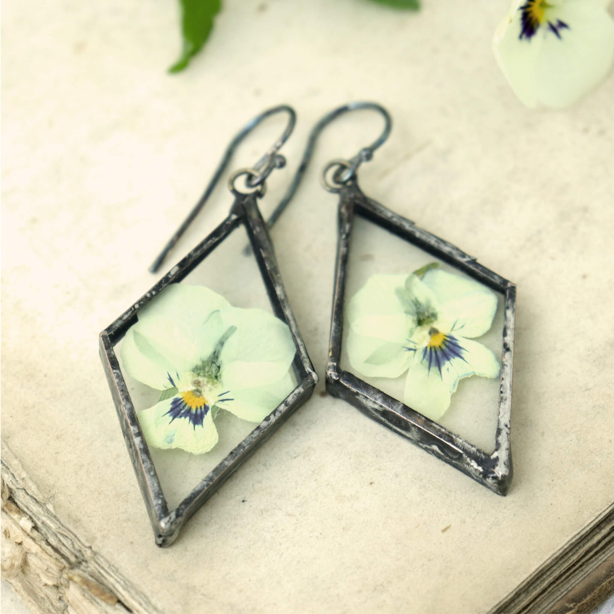 pansy earrings in triangular shape lying on a book