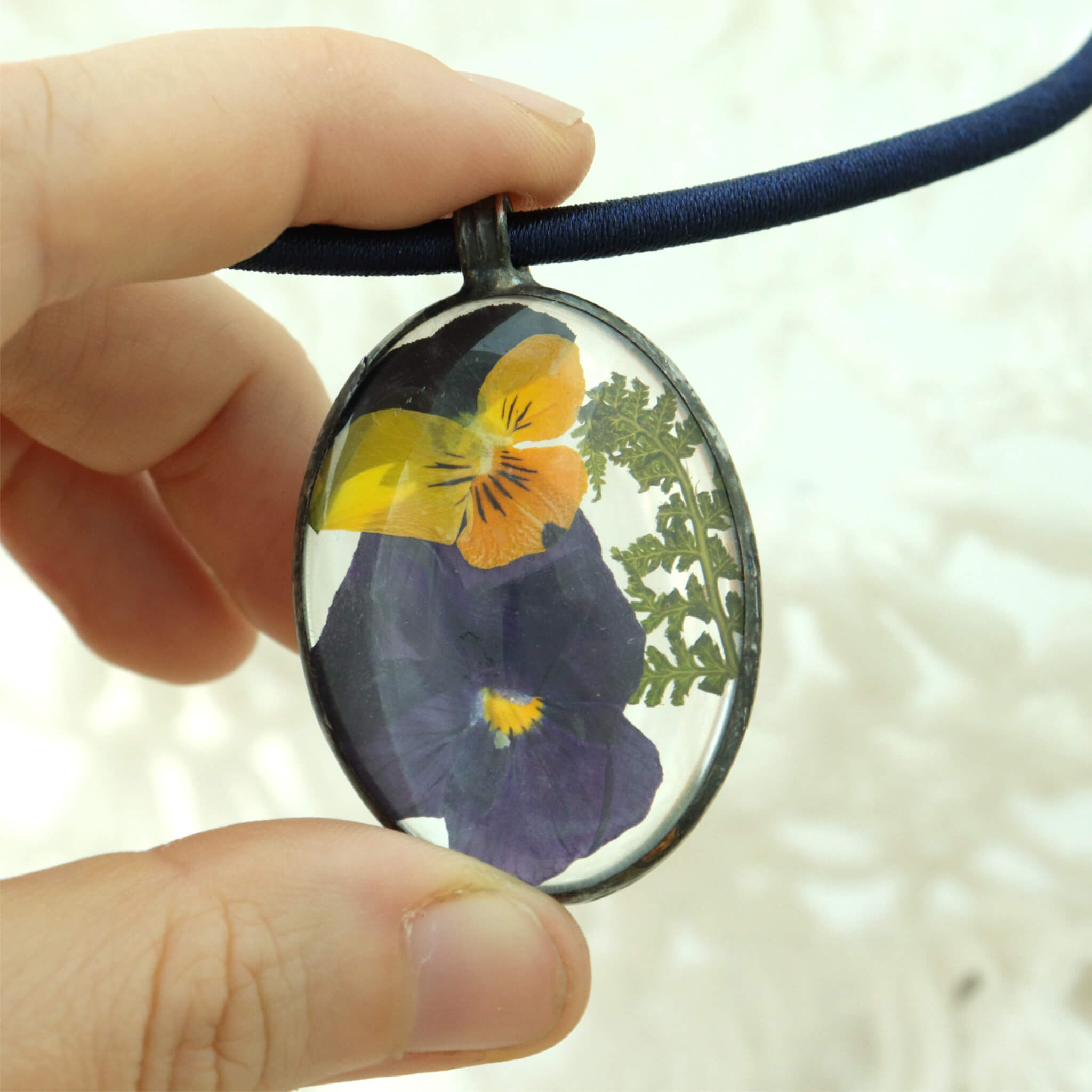 hand holding oval pansy necklace