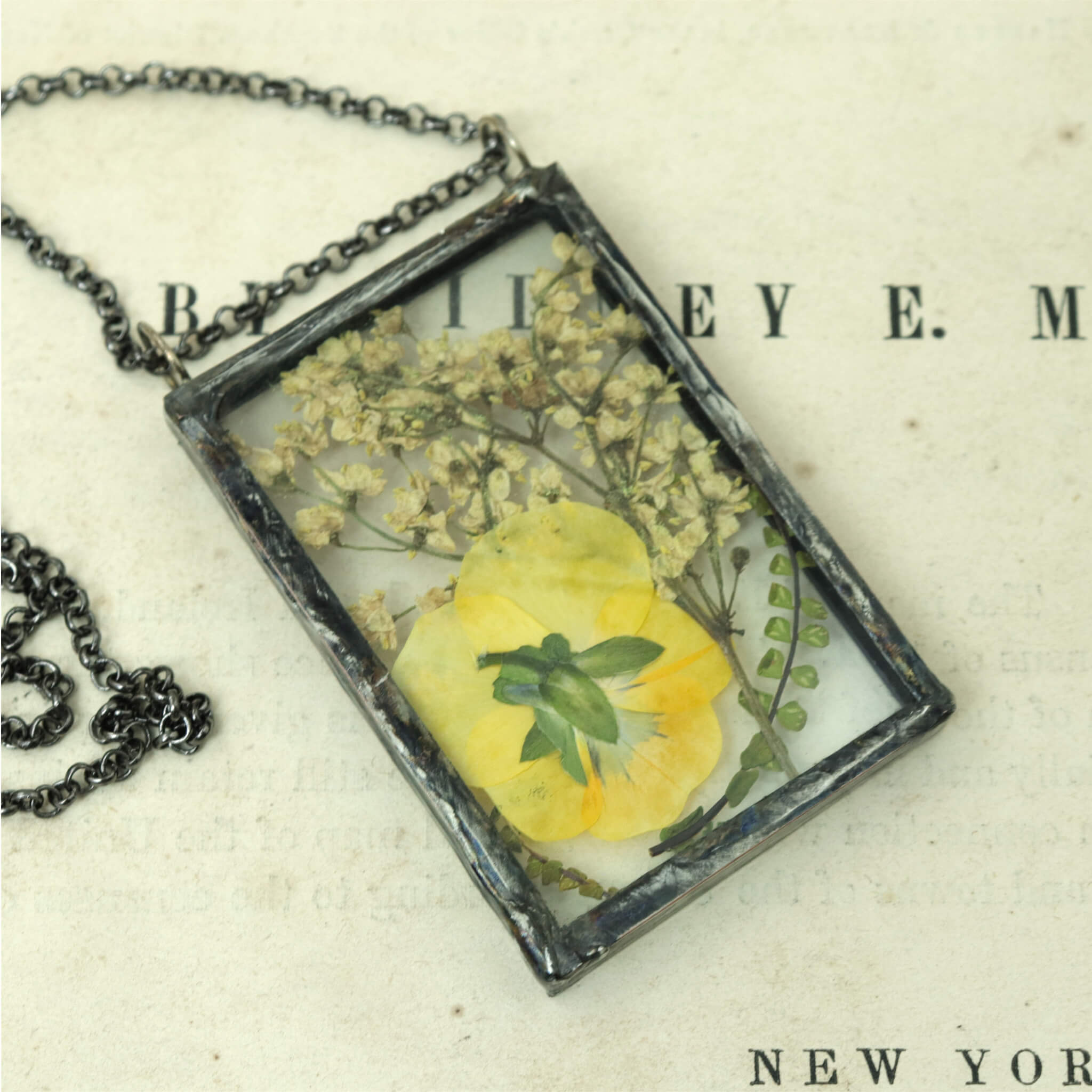 yellow Pansy necklace in rectangular shape lying on an old book