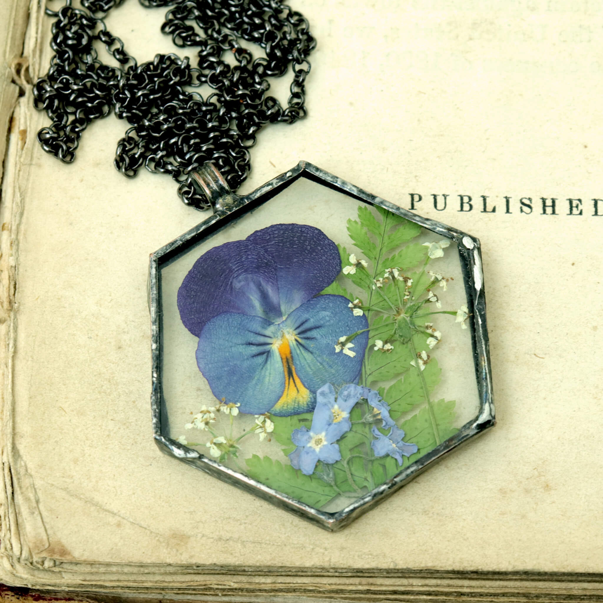 hexagonal violet pansy necklace lying on an old book