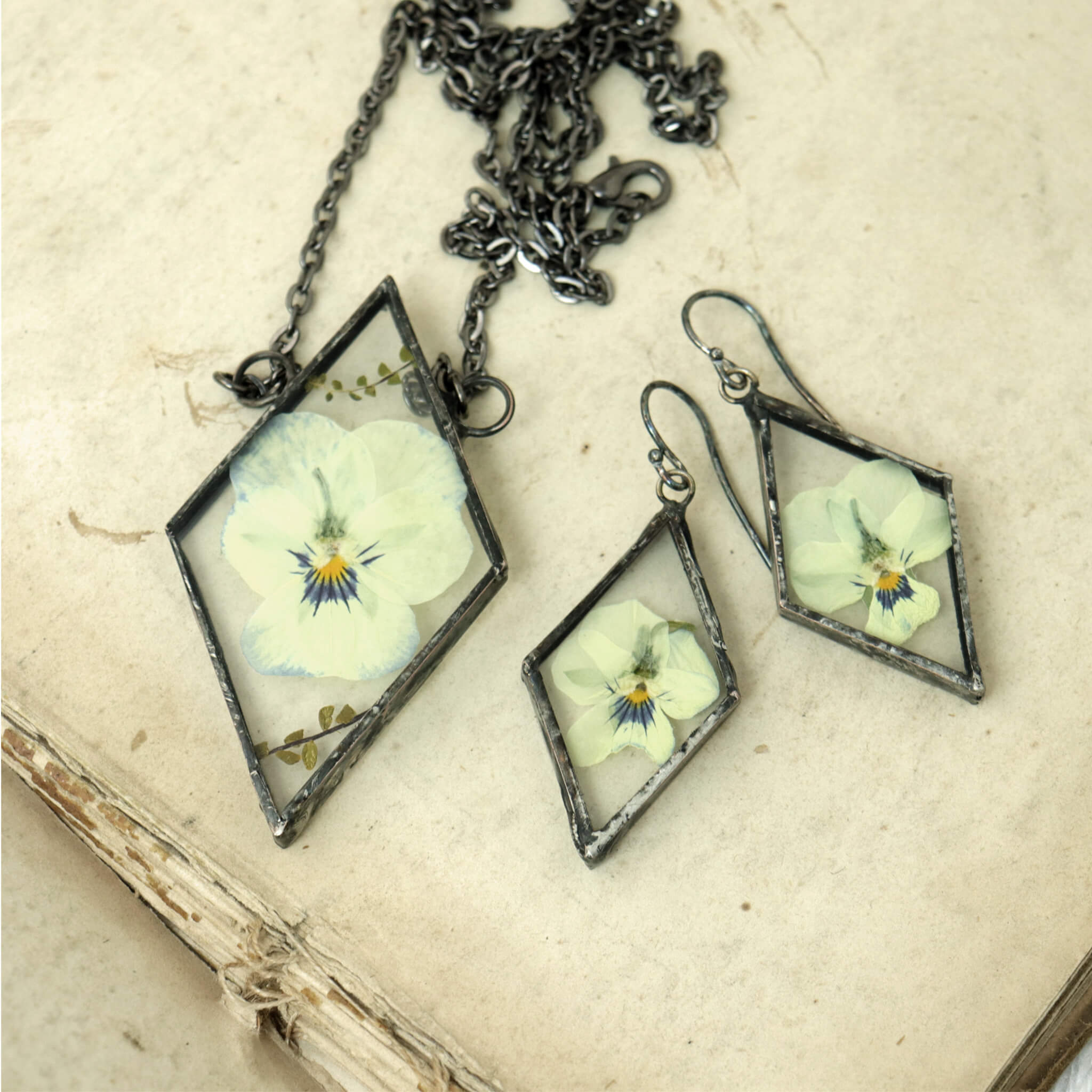 set of pansy earrings and necklace in triangular shape lying on a book