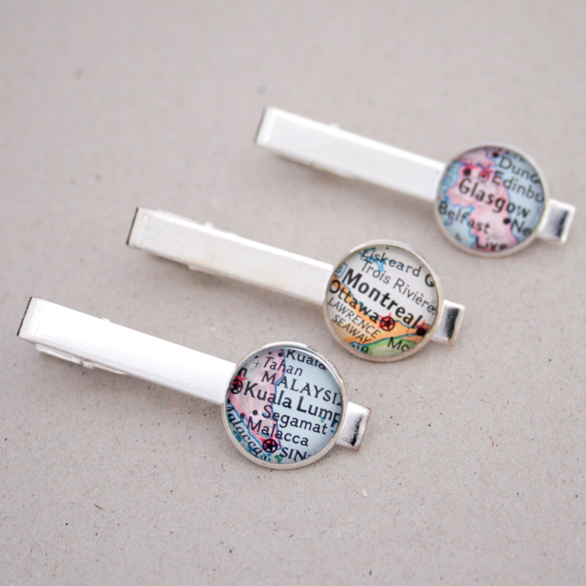 Three personalised tie clips in silver color featuring selection of maps