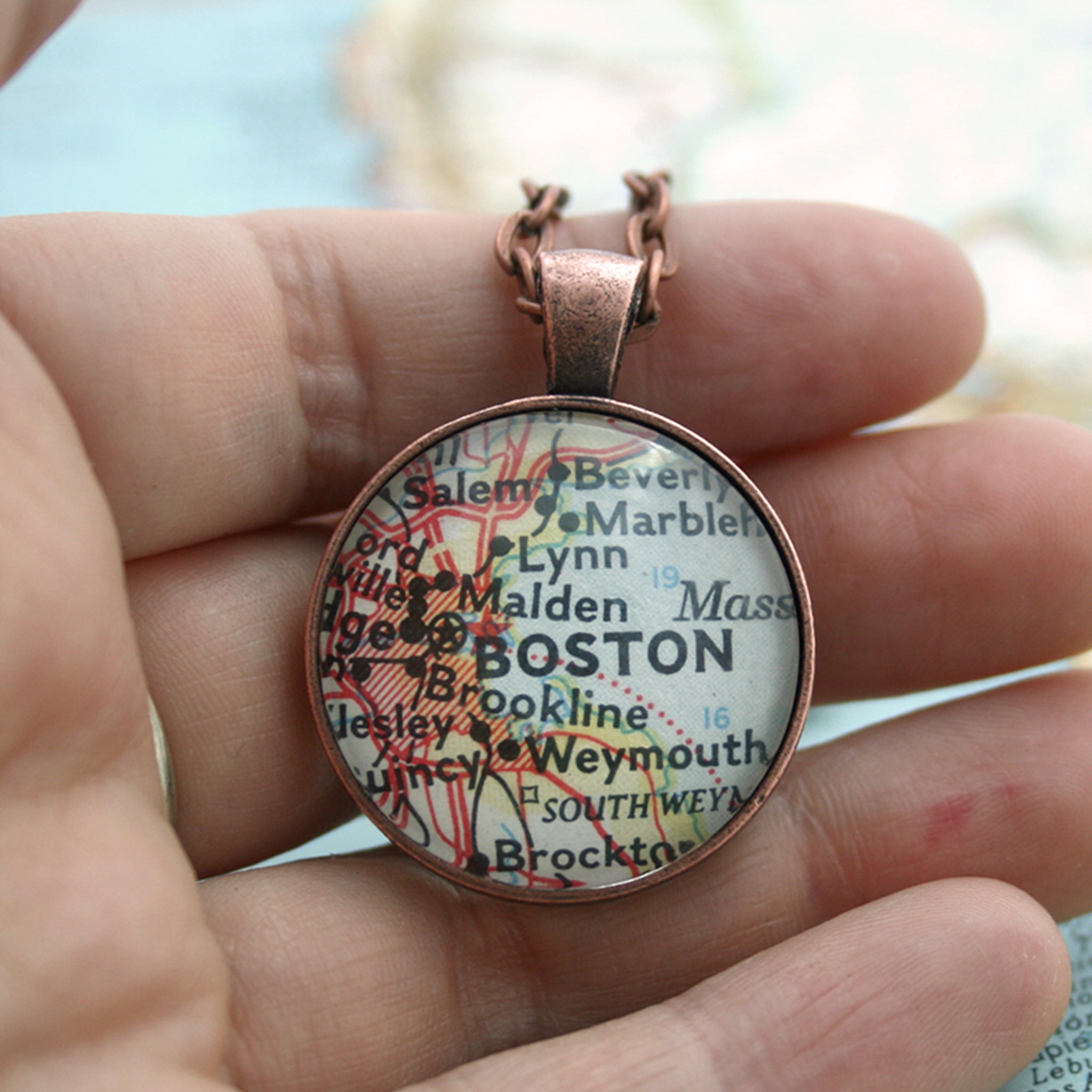 Copper double sided pendant necklace featuring map of Boston hold in hand