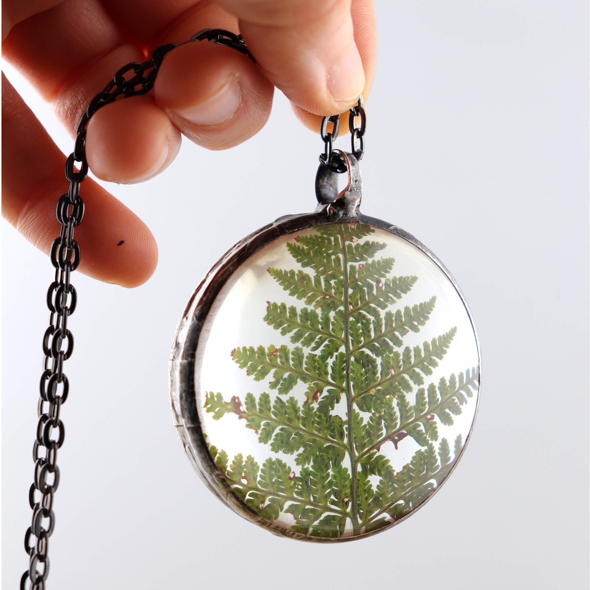 Fern necklace hold in hand to see through the glass
